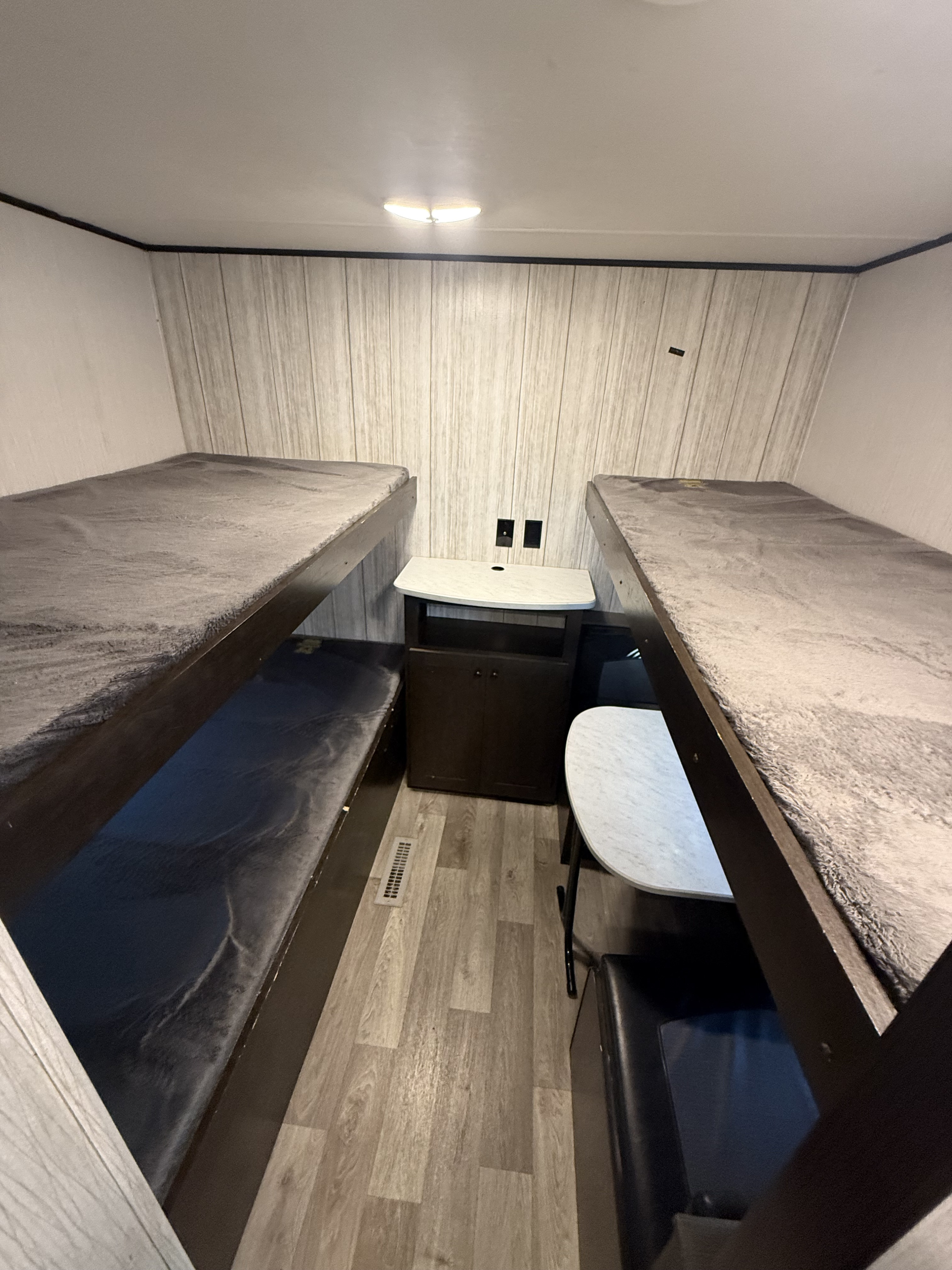 RV rental interior featuring stacked bunk beds, a central storage cabinet, and a compact dinette, offering efficient space.. Pioneer QB300 2021