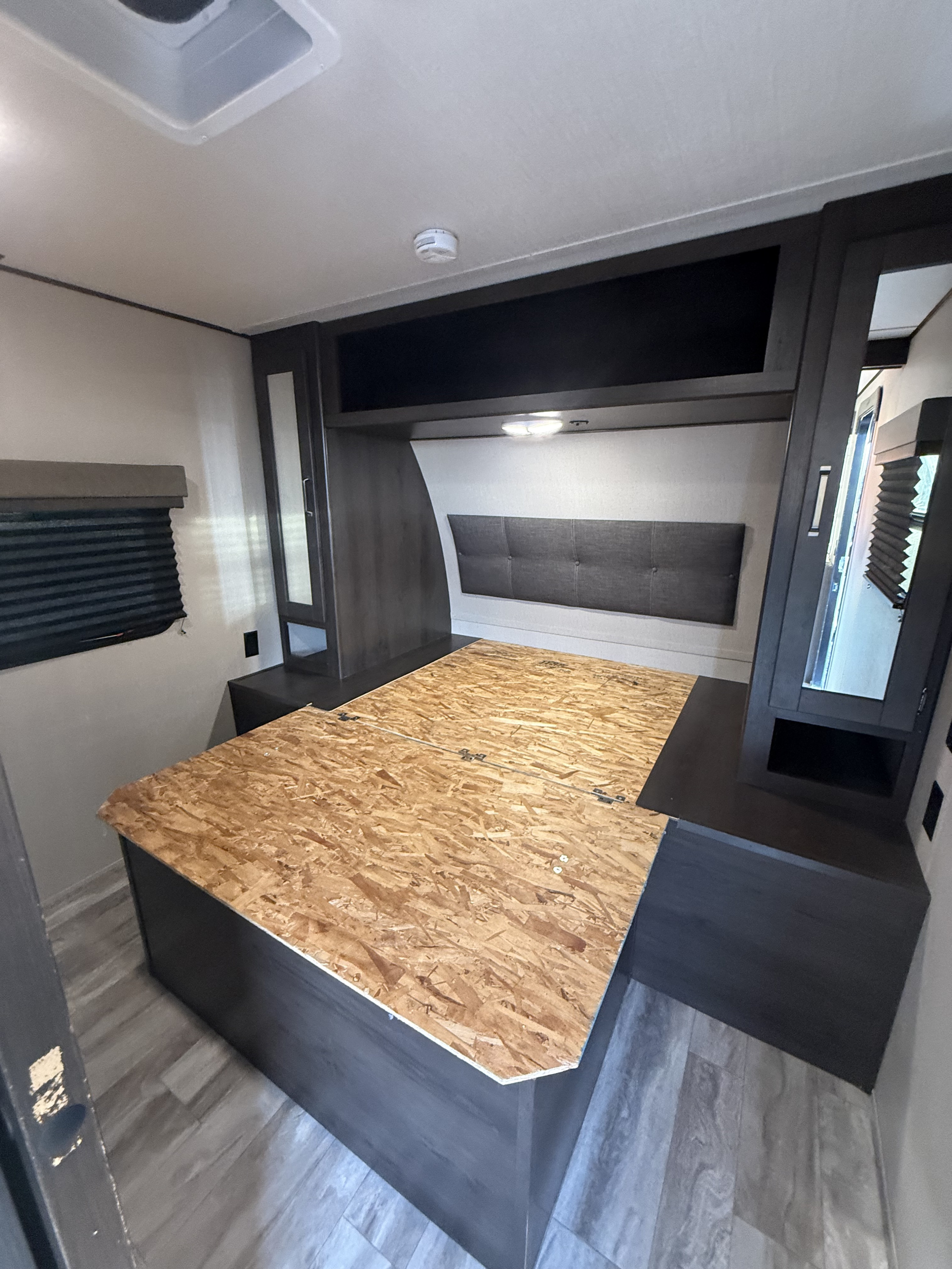 RV rental bedroom with dark cabinetry, upholstered headboard, and sturdy wooden bed base, ready for a mattress.. Transcend Xplor 260RB 2020