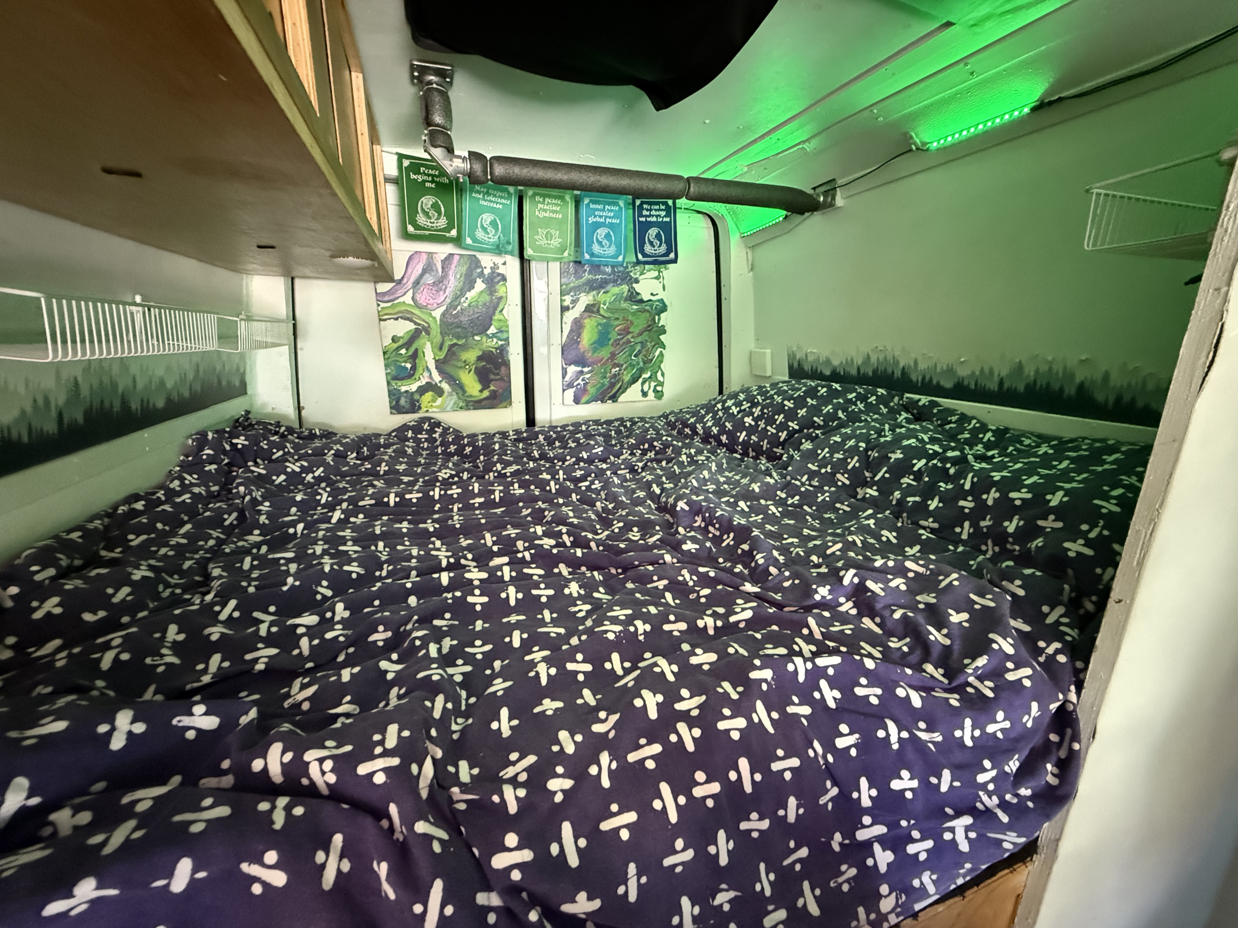 Cozy rv rental interior with a bed, artistic decor, peace flags, and green LED lighting, showcasing a personalized campervan setup.. Mercedes-Benz Sprinter RV Motorhome Campervan 2018