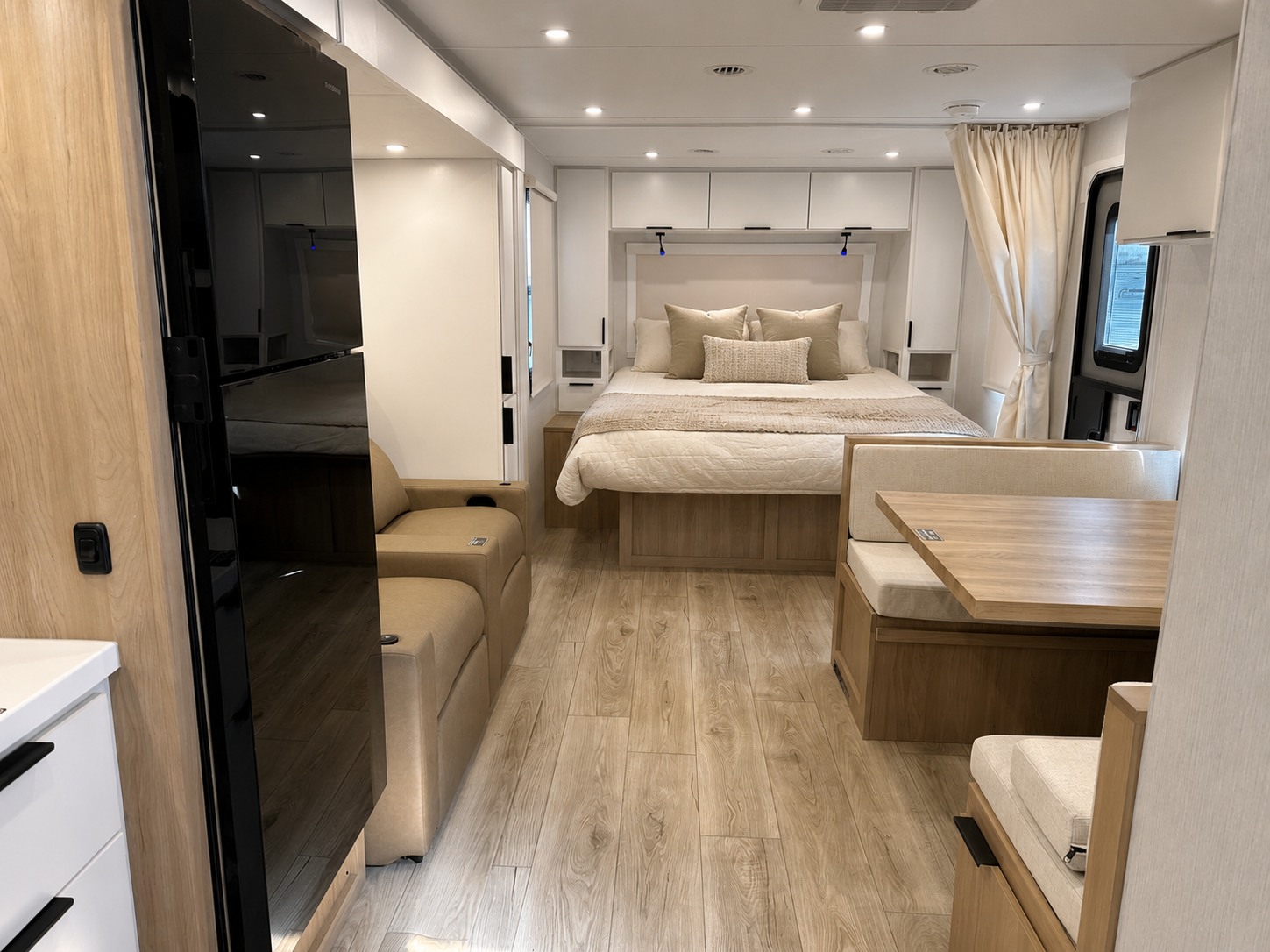 Spacious RV rental interior featuring a modern bedroom, dinette, and sofa. Bright, comfortable, and ready for adventure.. Winnebago Thrive 2026