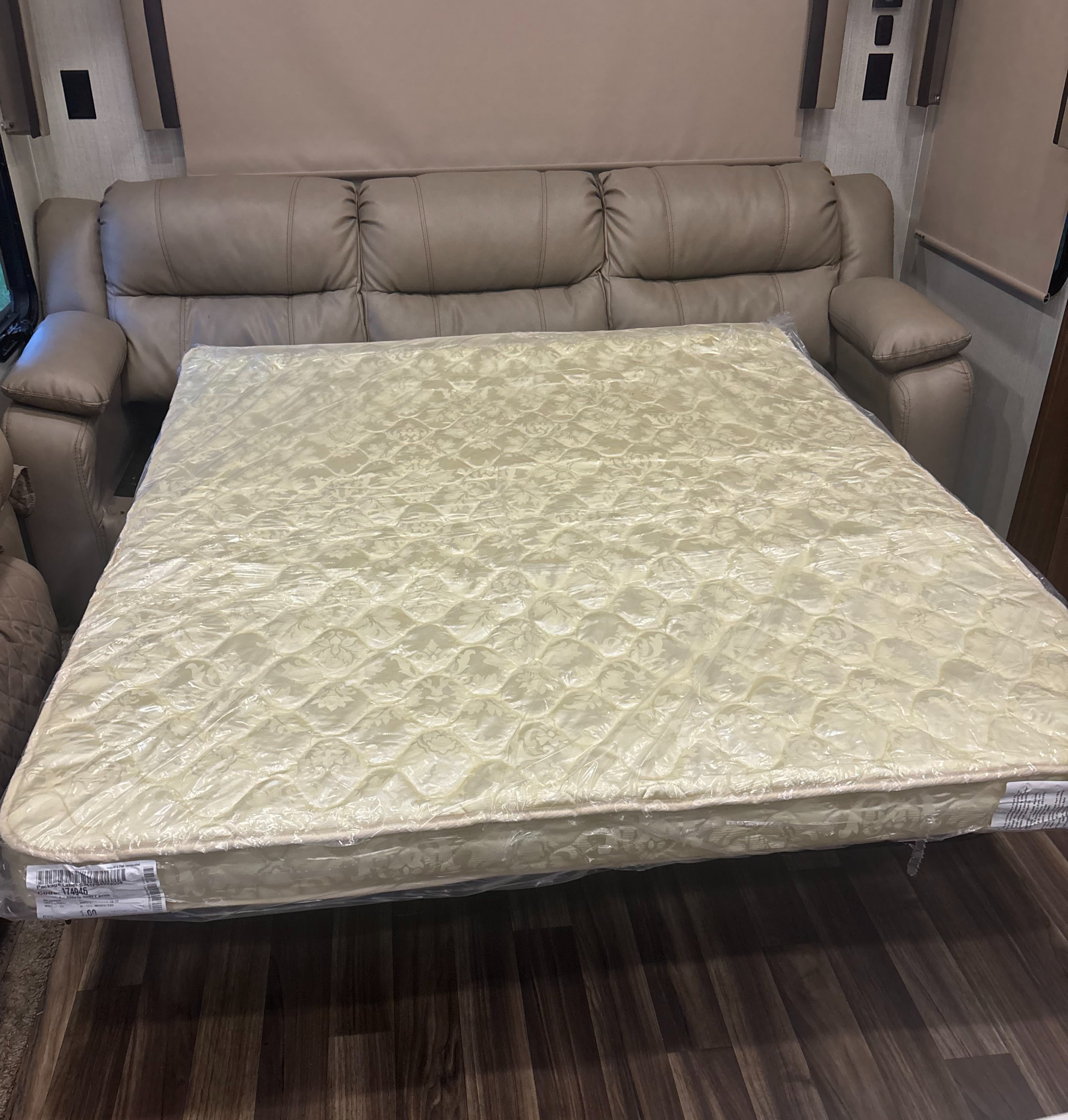An RV rental's extended sofa bed, featuring a new, plastic-wrapped mattress, ready for comfortable sleep.. Forest River Cardinal 2018