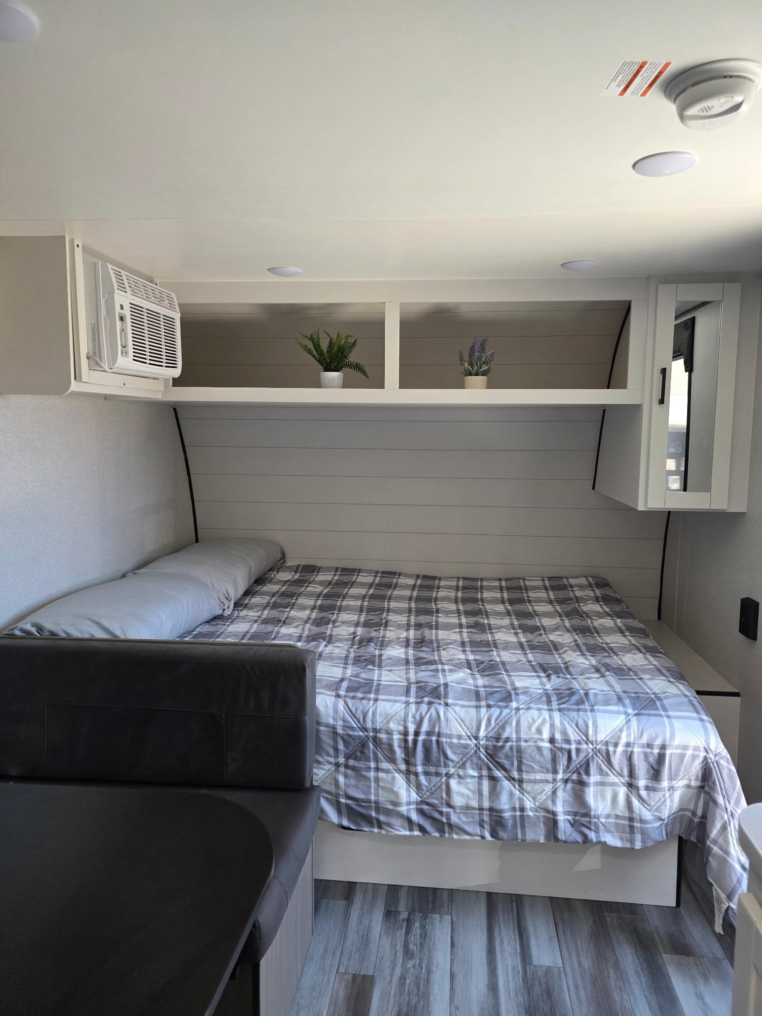 RV rental interior: cozy bed with plaid comforter, dinette seating, overhead storage, and AC for a comfortable journey.. Jayco Jayco 2026
