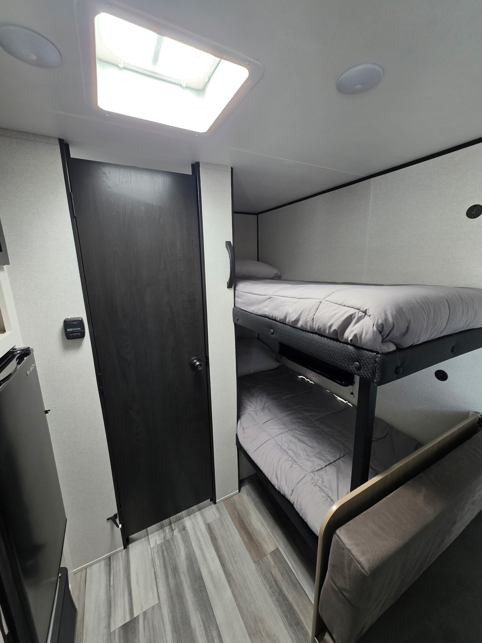 Cozy RV rental interior showcasing bunk beds with grey bedding, a skylight, wood-look flooring, and a small sofa for guests.. Jayco Jayco 2026