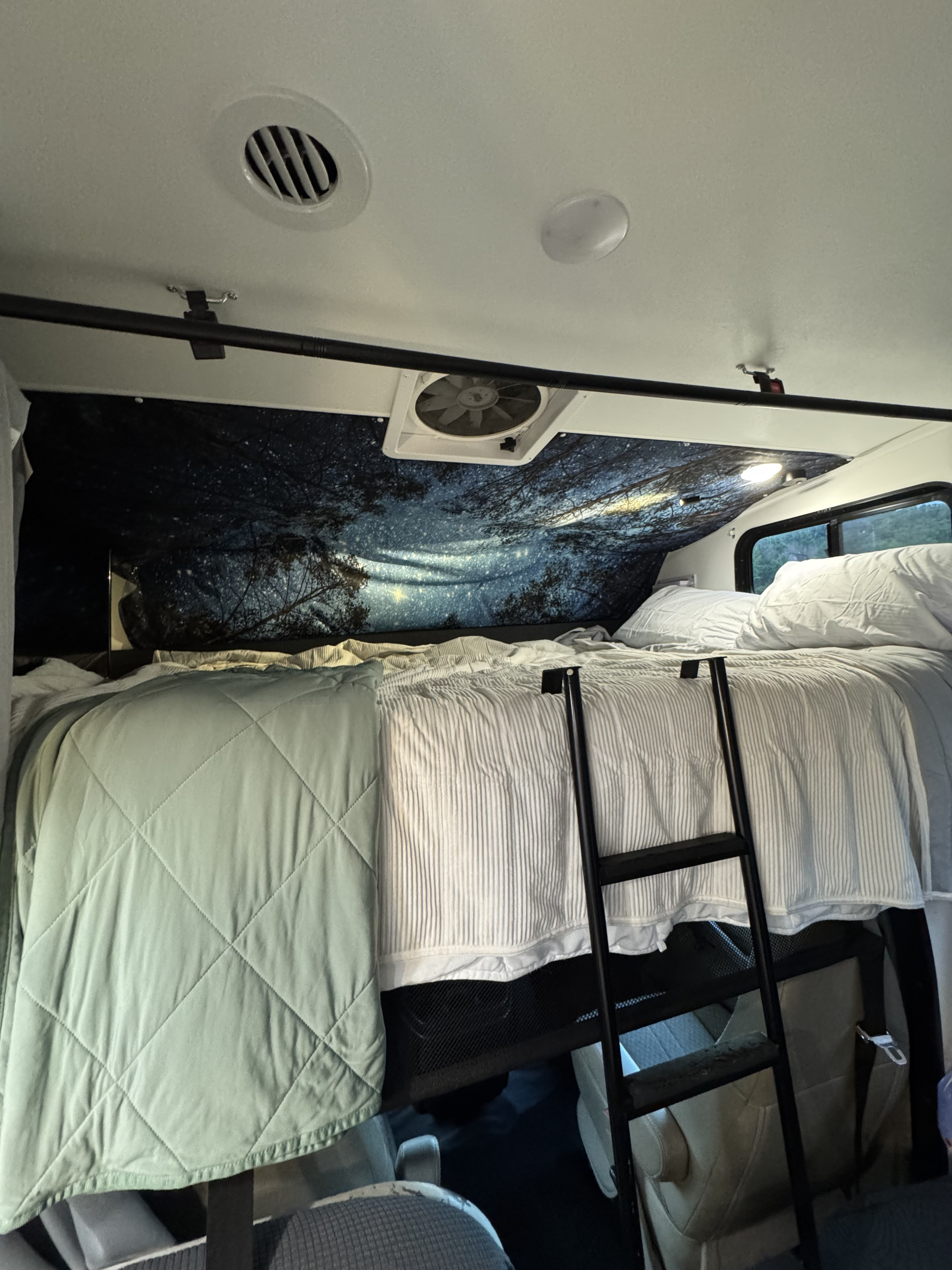 RV rental interior: A cozy bunk bed with a ladder, starry night mural, and comfortable bedding for a snug travel experience.. Forest River Coachmen Freelander 2017