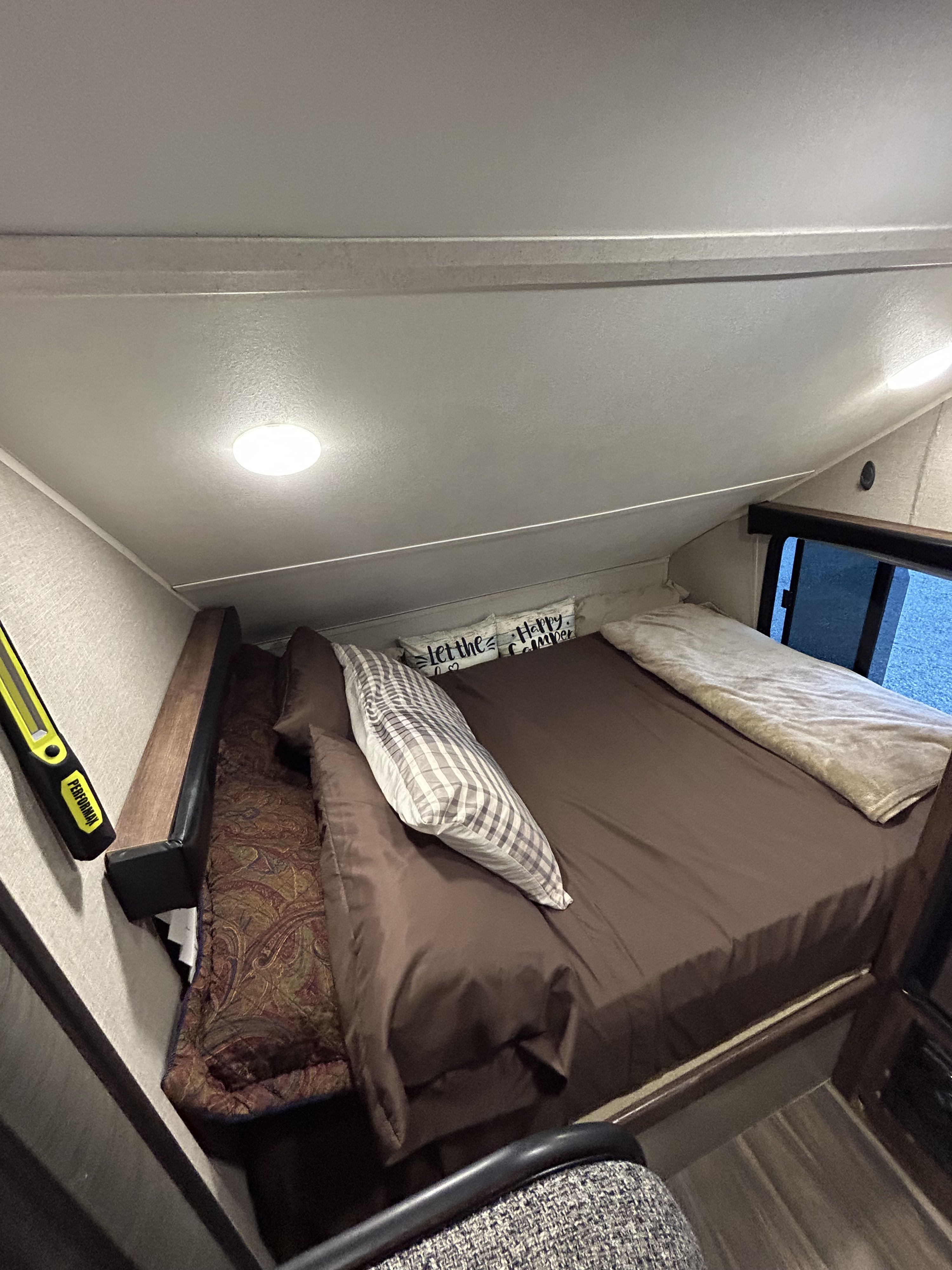 Compact RV rental bedroom featuring a slanted ceiling, comfortable bed, overhead light, and window.. Travel Lite Falcon 2018