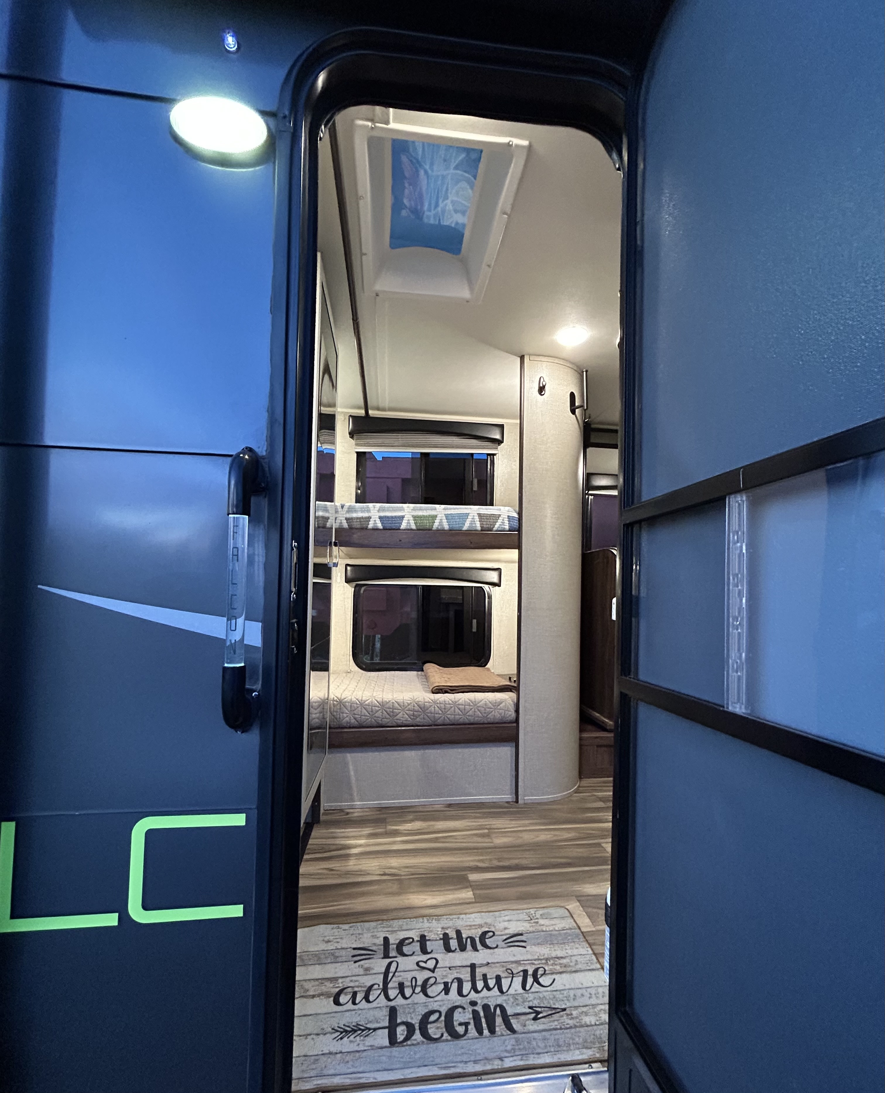 Explore this modern RV rental interior! Features comfy bunk beds, a skylight, and an adventure-themed welcome mat.. Travel Lite Falcon 2018