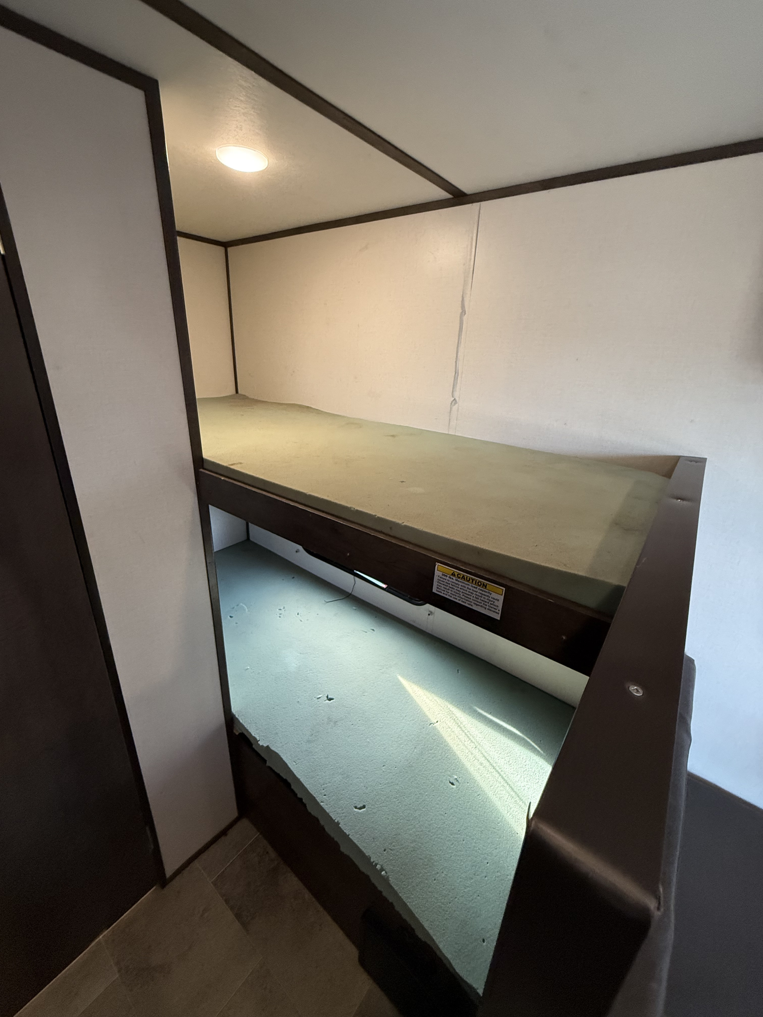 Inside an RV rental, showing the built-in bunk beds with foam mattresses and task lighting, ideal for compact sleeping.. Coleman 17B Dutchmen 2022