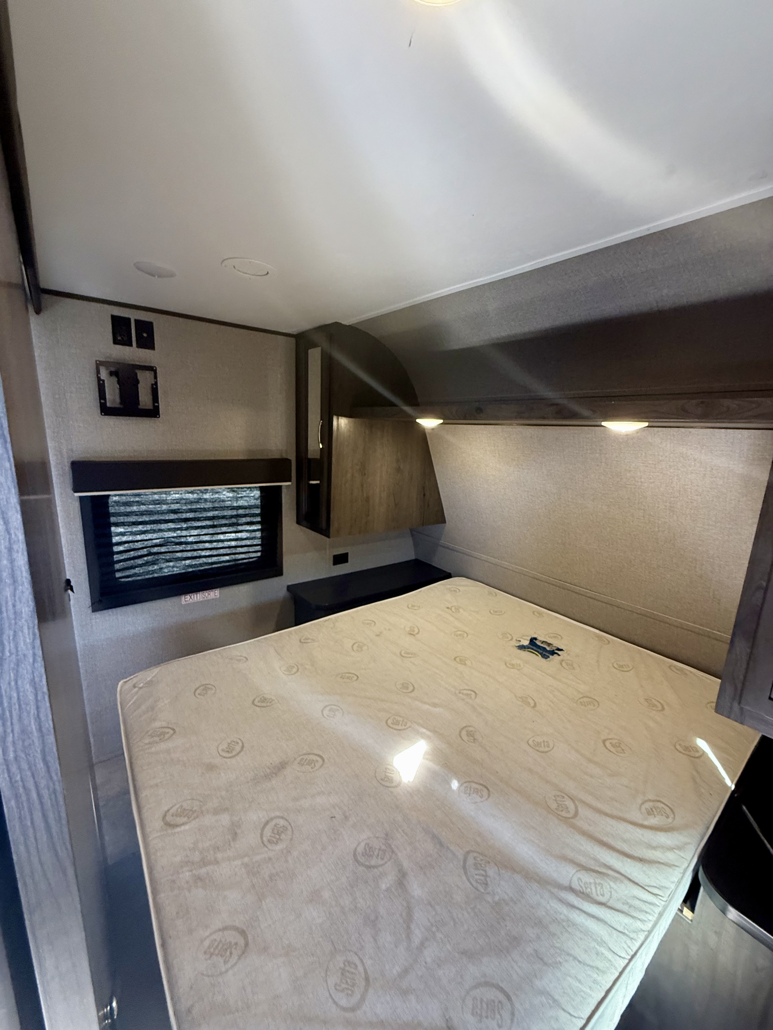 RV rental bedroom with a prominent Serta mattress, a window with blinds, and a wall-mounted TV bracket.. Jayco 267BHSW 2021