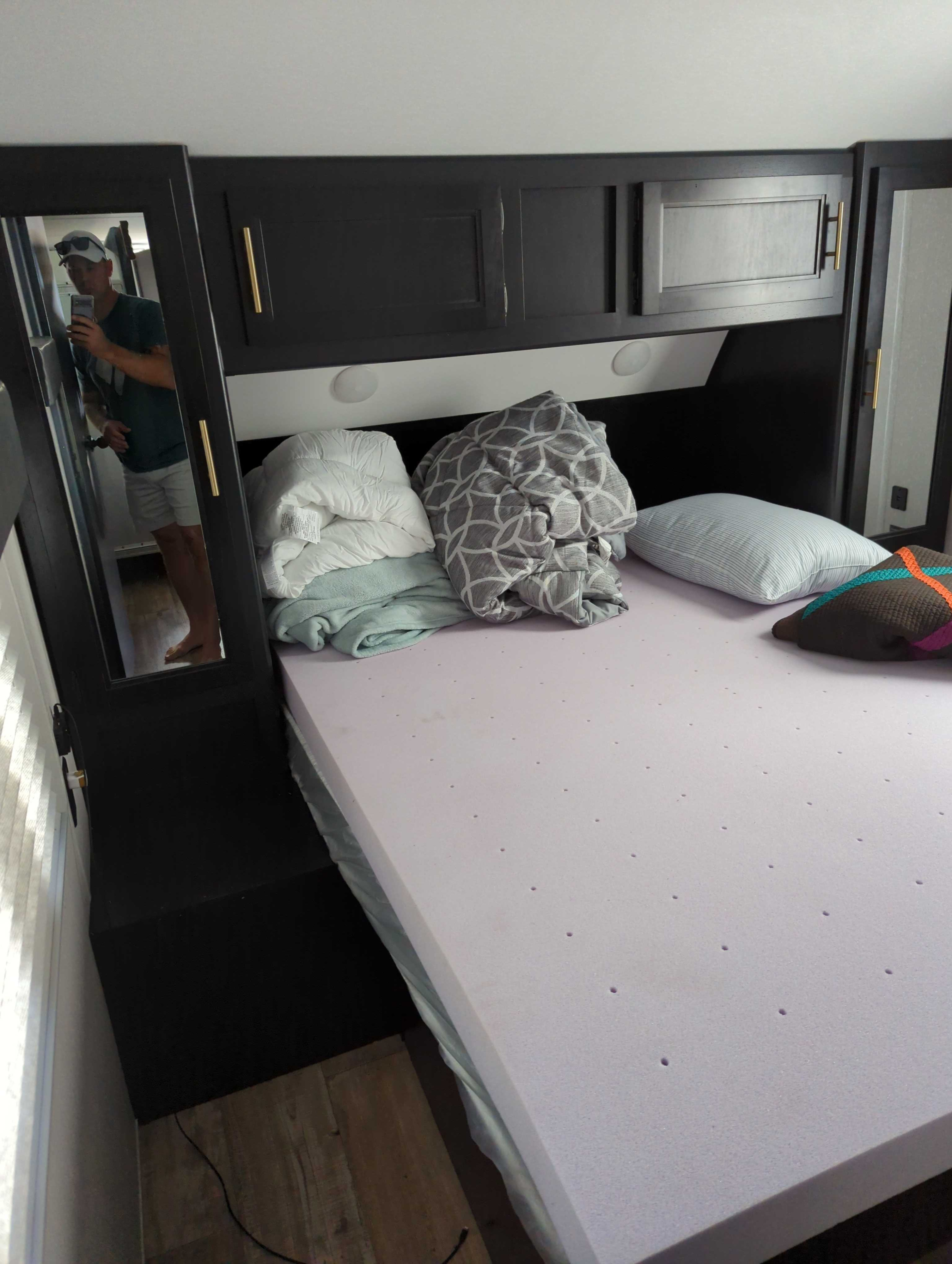 This RV rental bedroom features a purple foam mattress topper, dark storage cabinets, and a large mirror.. Forest River Cherokee Grey Wolf 2021