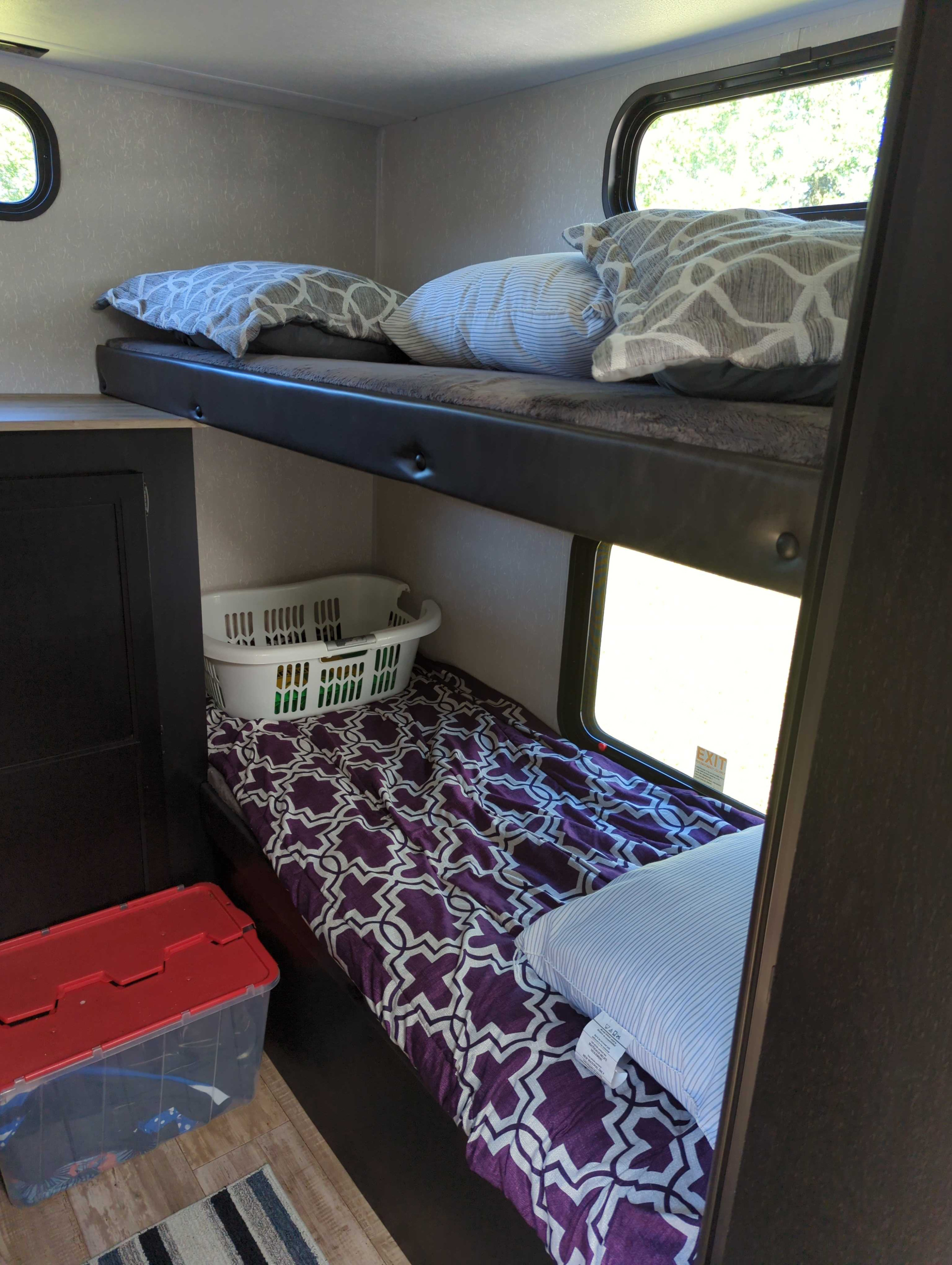RV rental bunk beds with colorful bedding, windows, and storage. A practical and cozy sleeping space inside a recreational vehicle.. Forest River Cherokee Grey Wolf 2021