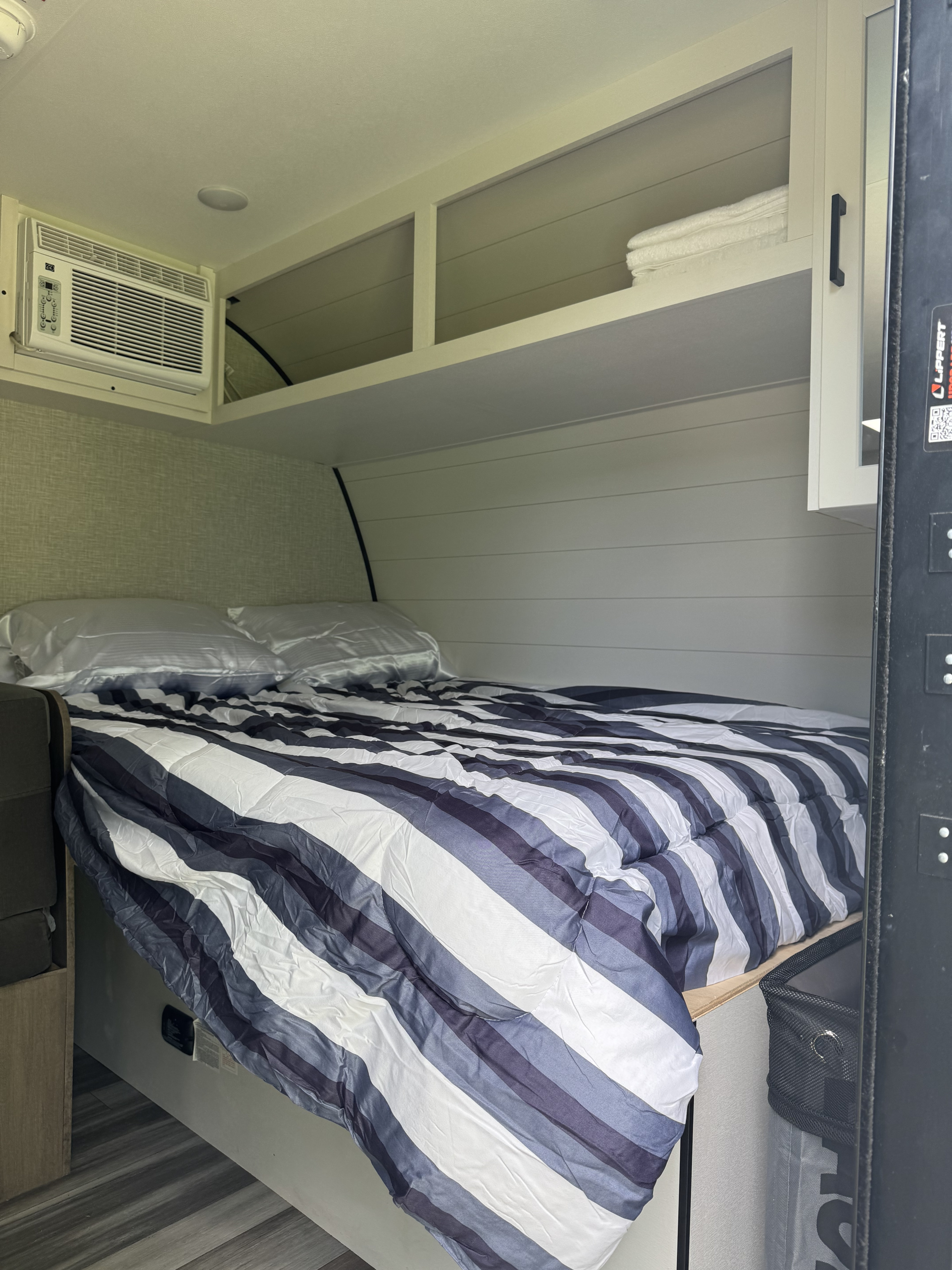 Cozy RV rental bedroom with striped bedding, AC, overhead storage, and clean towels, ready for a comfortable stay.. Jayco Jay Flight SLX 2025