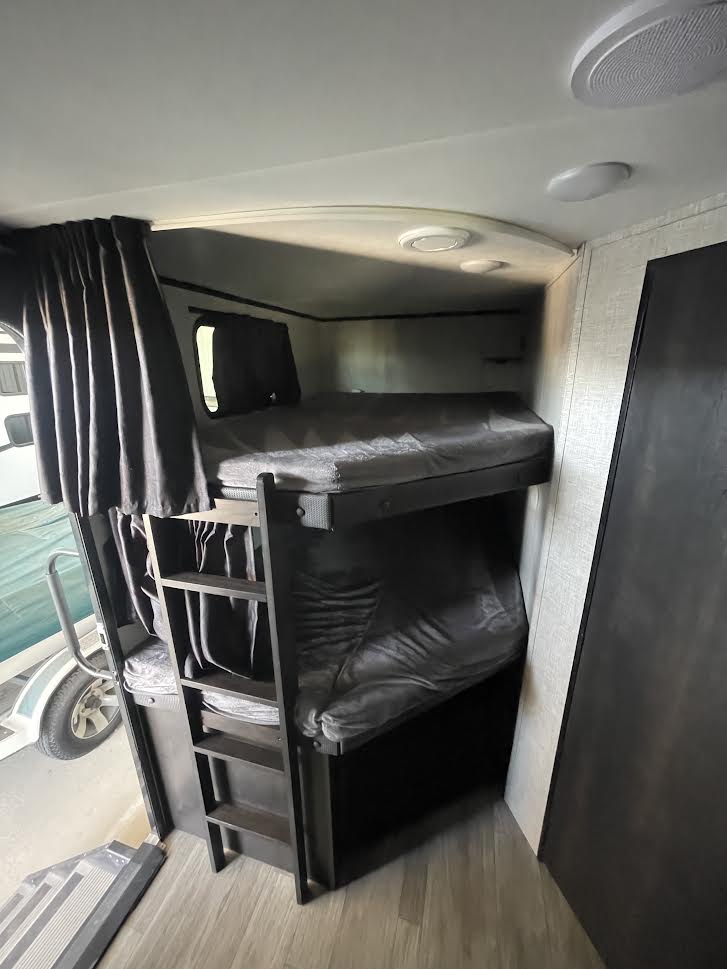 RV rental: Dark bunk beds with ladder, mattresses, & curtains, providing a cozy sleeping area inside.. Jayco Jay Feather 2022