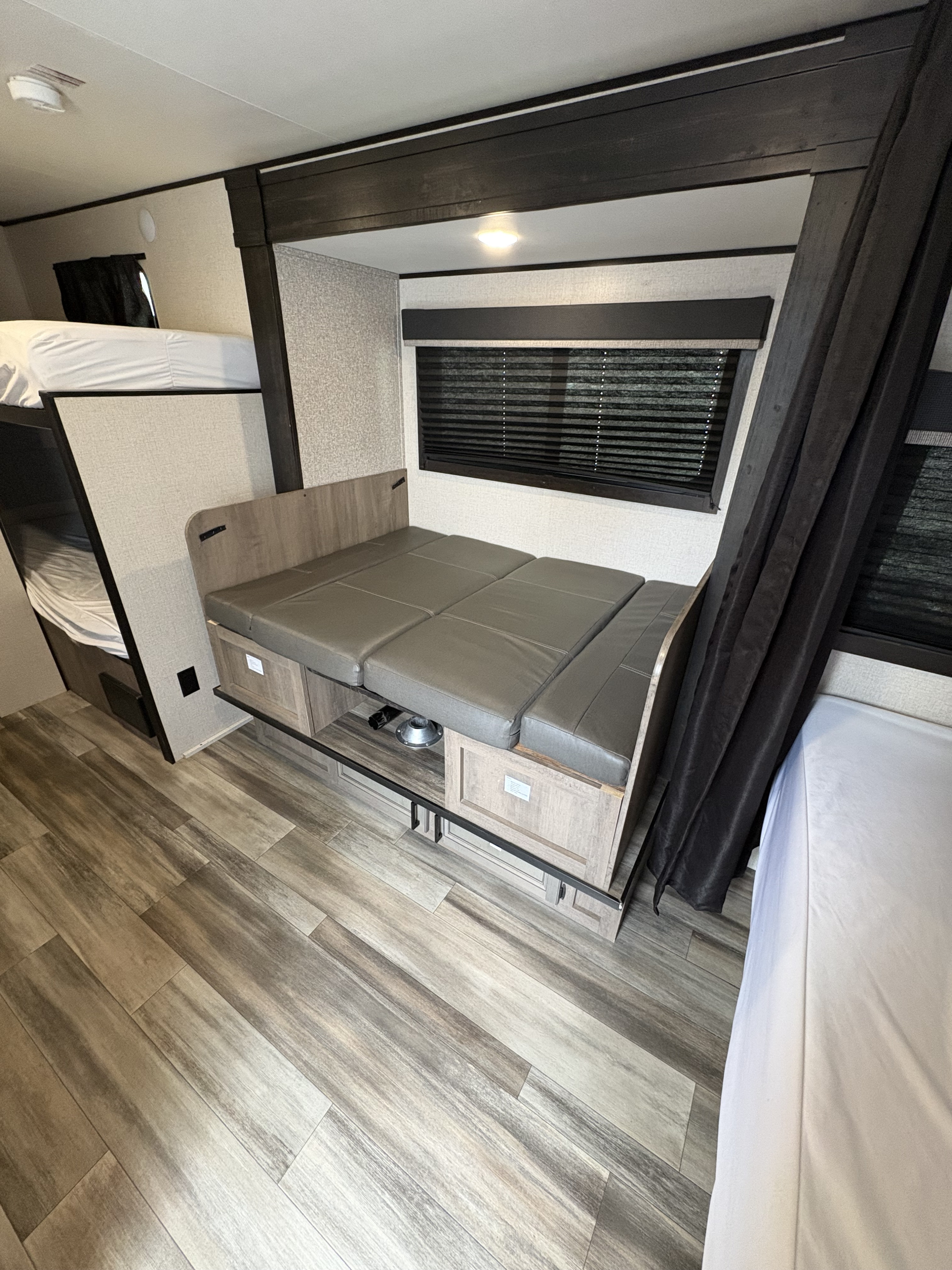 RV rental interior: cozy dinette converts to a bed, beside bunk beds & wood-look floor. Perfect for family campers.. Highland Ridge RV Open Range 2022