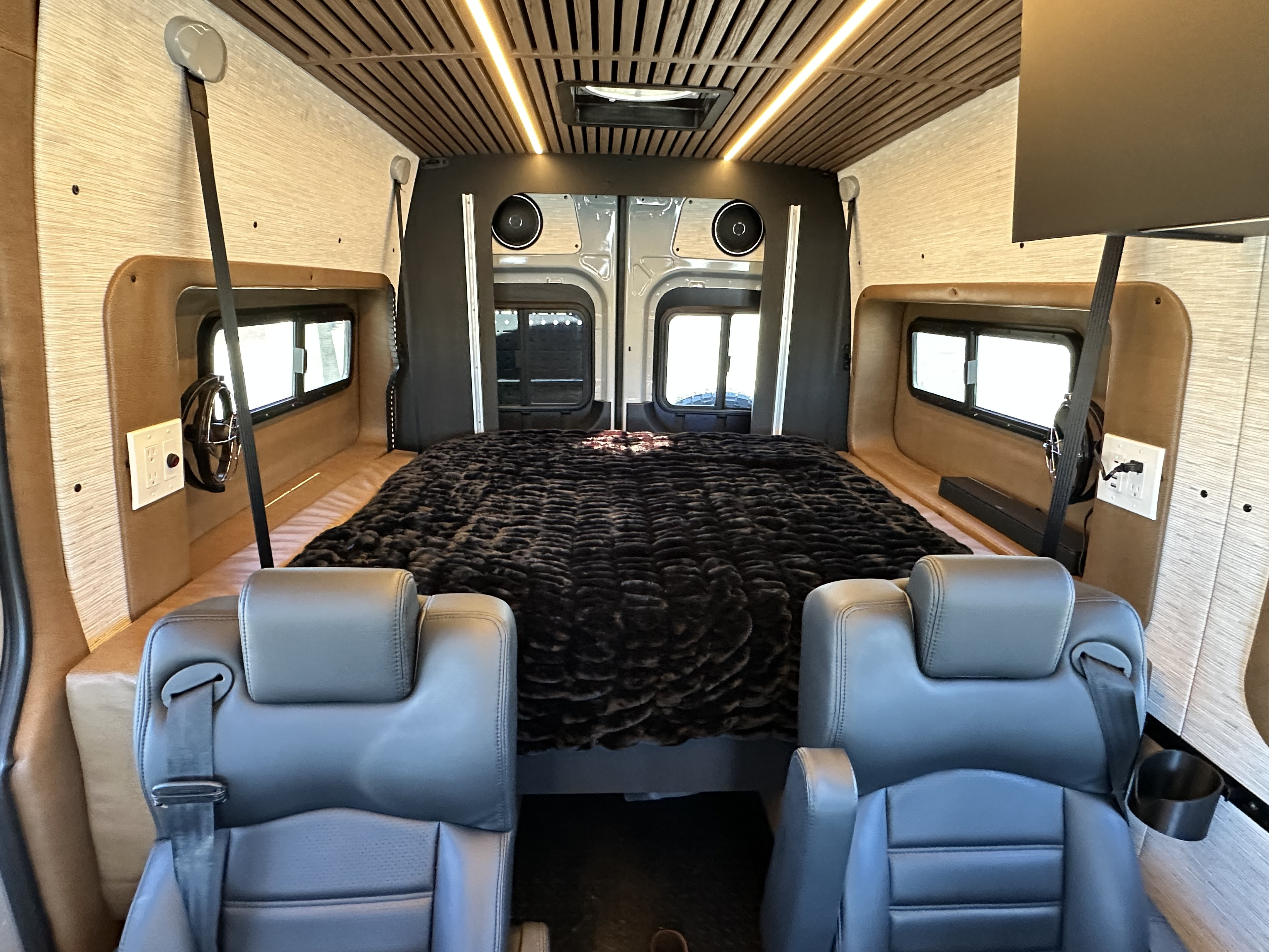 Spacious RV rental interior with comfortable seating, a plush bed, panoramic windows, and ambient lighting for your next adventure.. Rogue Van Rogue Van Class B 2025