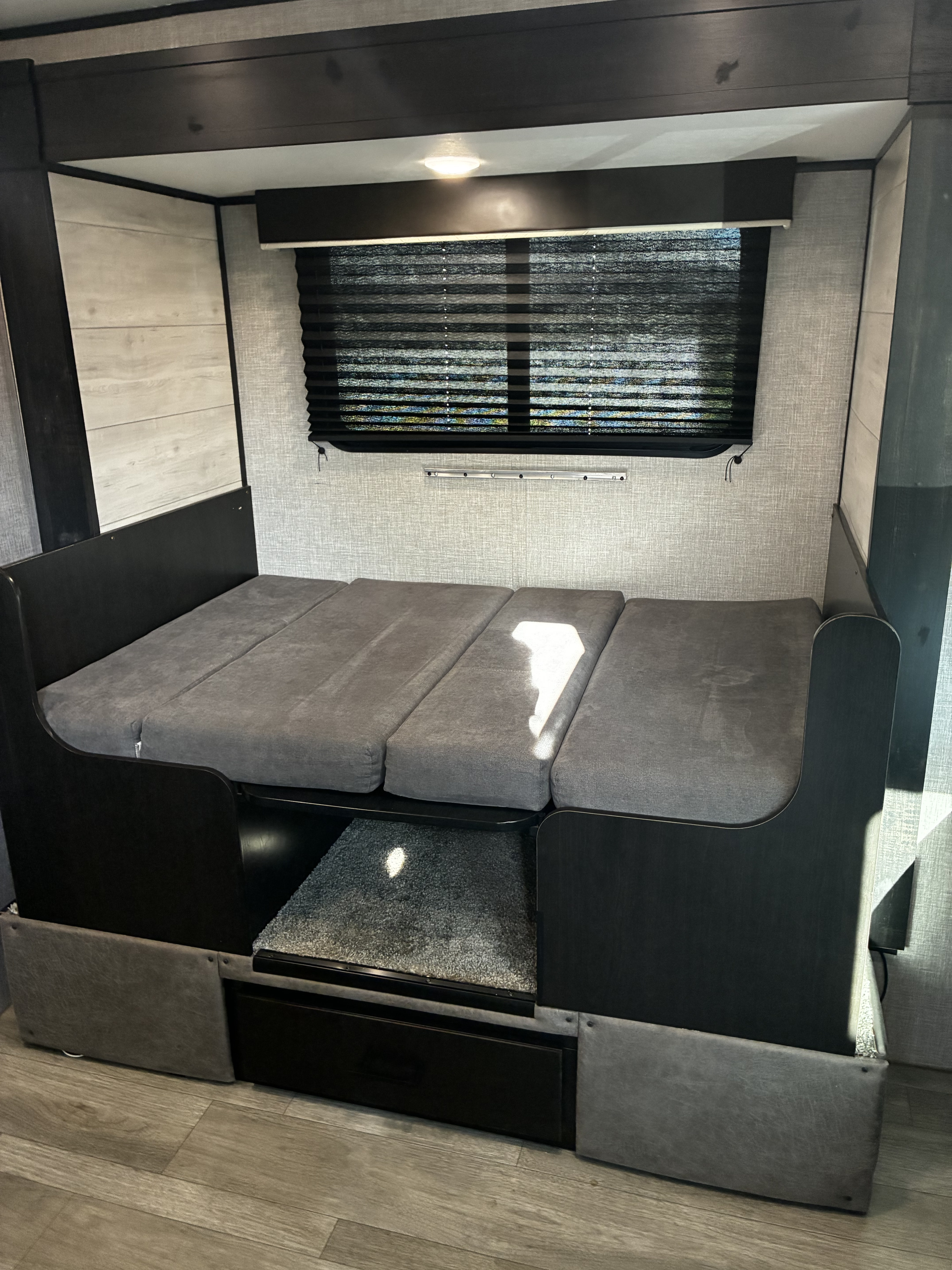 RV rental: A dark wood and grey cushioned dinette/bunk area, with a window, carpeted step, and storage drawer.. Jayco Jay Flight SLX Baja Edition 2022