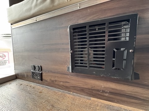 An RV rental interior shows a black furnace vent, USB ports, and electrical outlets on a wood-grain panel.. Carado Carado Class B 2019