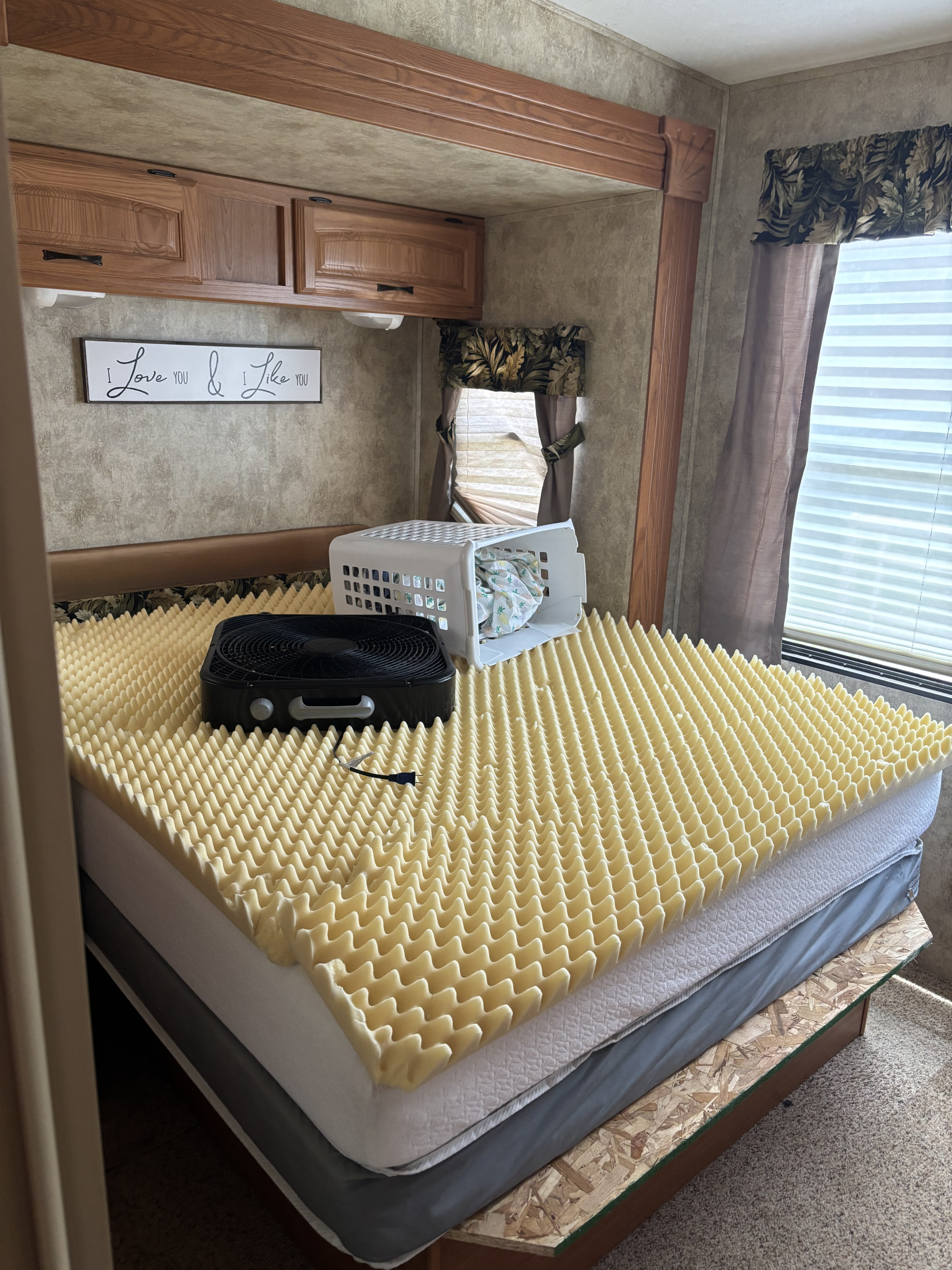 RV rental bedroom with a bed featuring a foam topper, fan, and laundry basket, highlighting sleep comfort.. Keystone RV Laredo 2007