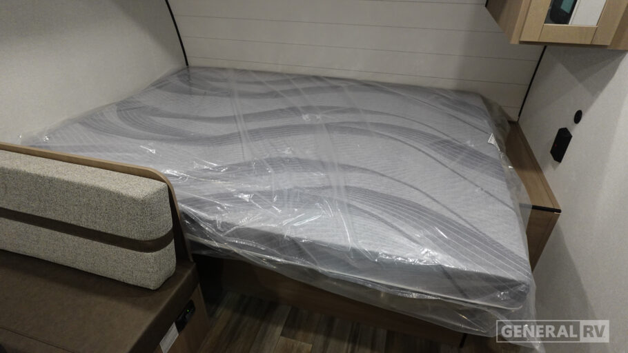 RV rental bedroom with a new mattress still in plastic wrapping and an adjacent upholstered sofa.. Open Range Colt 2026