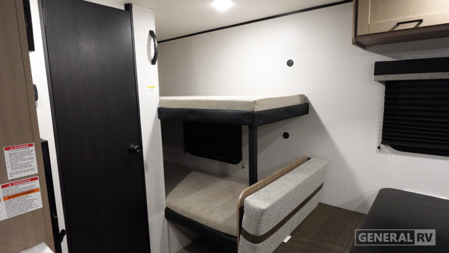 Inside an rv rental, showing bunk beds, a compact seating area, a privacy door, and a window with blinds.. Open Range Colt 2026