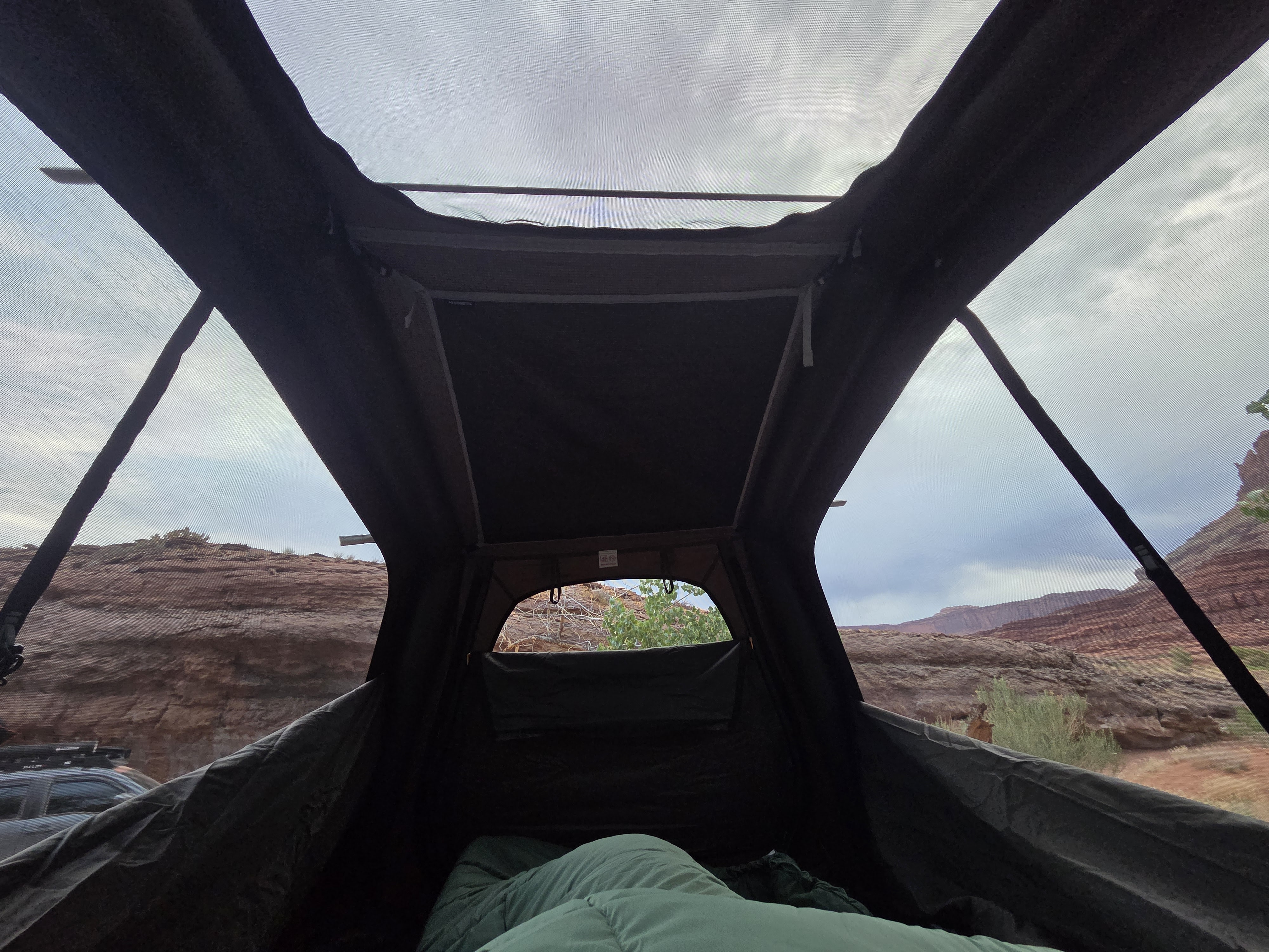 Relaxing inside a rooftop tent, looking out at a stunning red rock desert landscape. Ideal for an RV rental camping trip.. Jeep Gladiator 2020