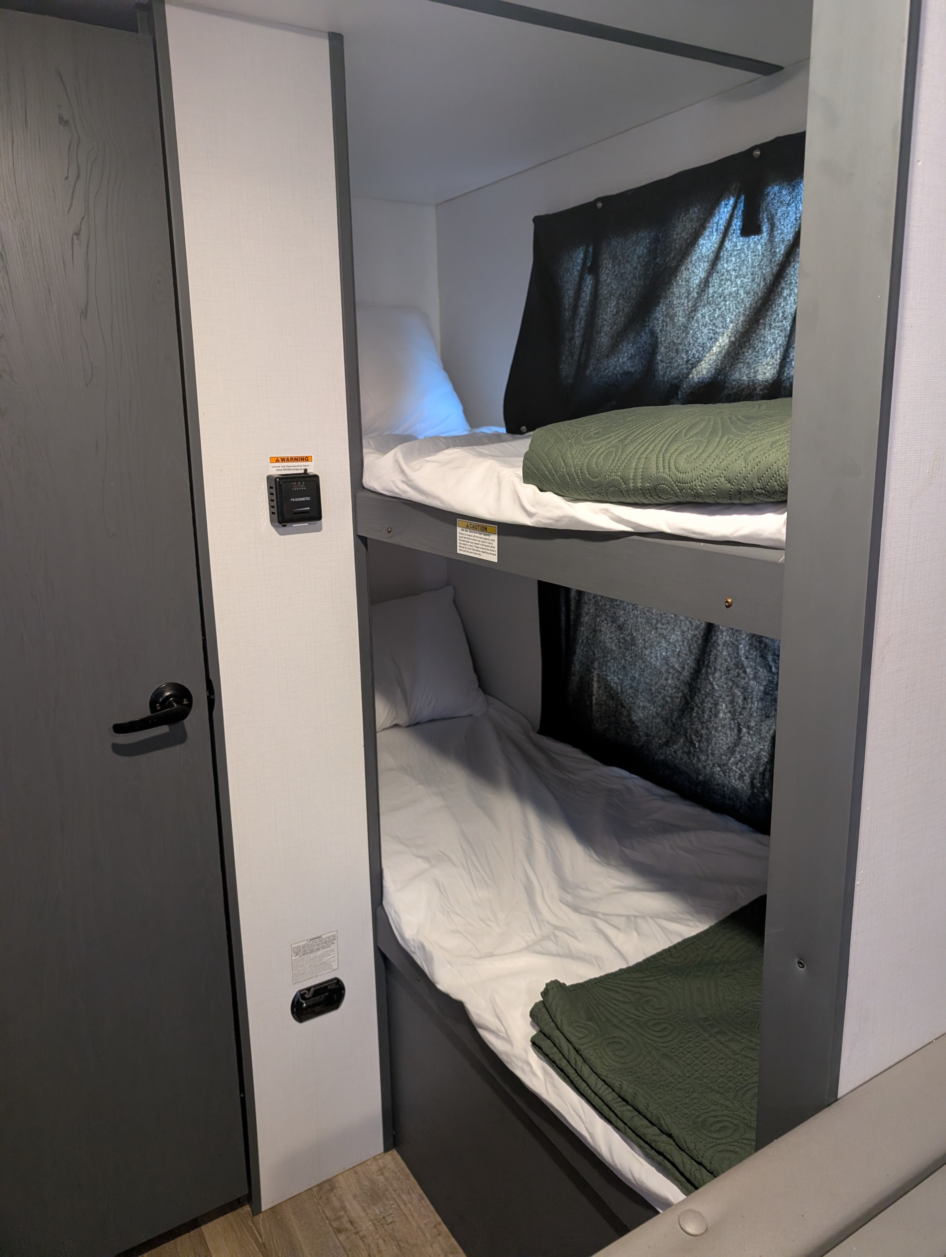 Cozy bunk beds for an RV rental adventure, complete with white linens, a green blanket, and a Dometic thermostat.. Keystone RV Bullet Crossfire 2021