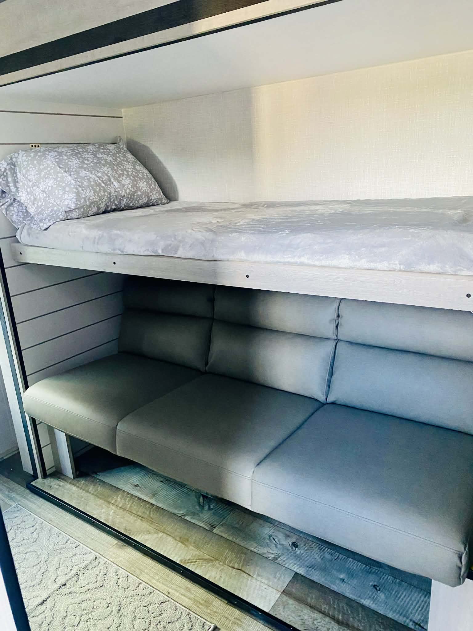 RV rental interior: A top bunk with patterned bedding over a three-cushion gray sofa. Versatile camper accommodations.. Crossroads RV Sunset Trail Super Lite 2025
