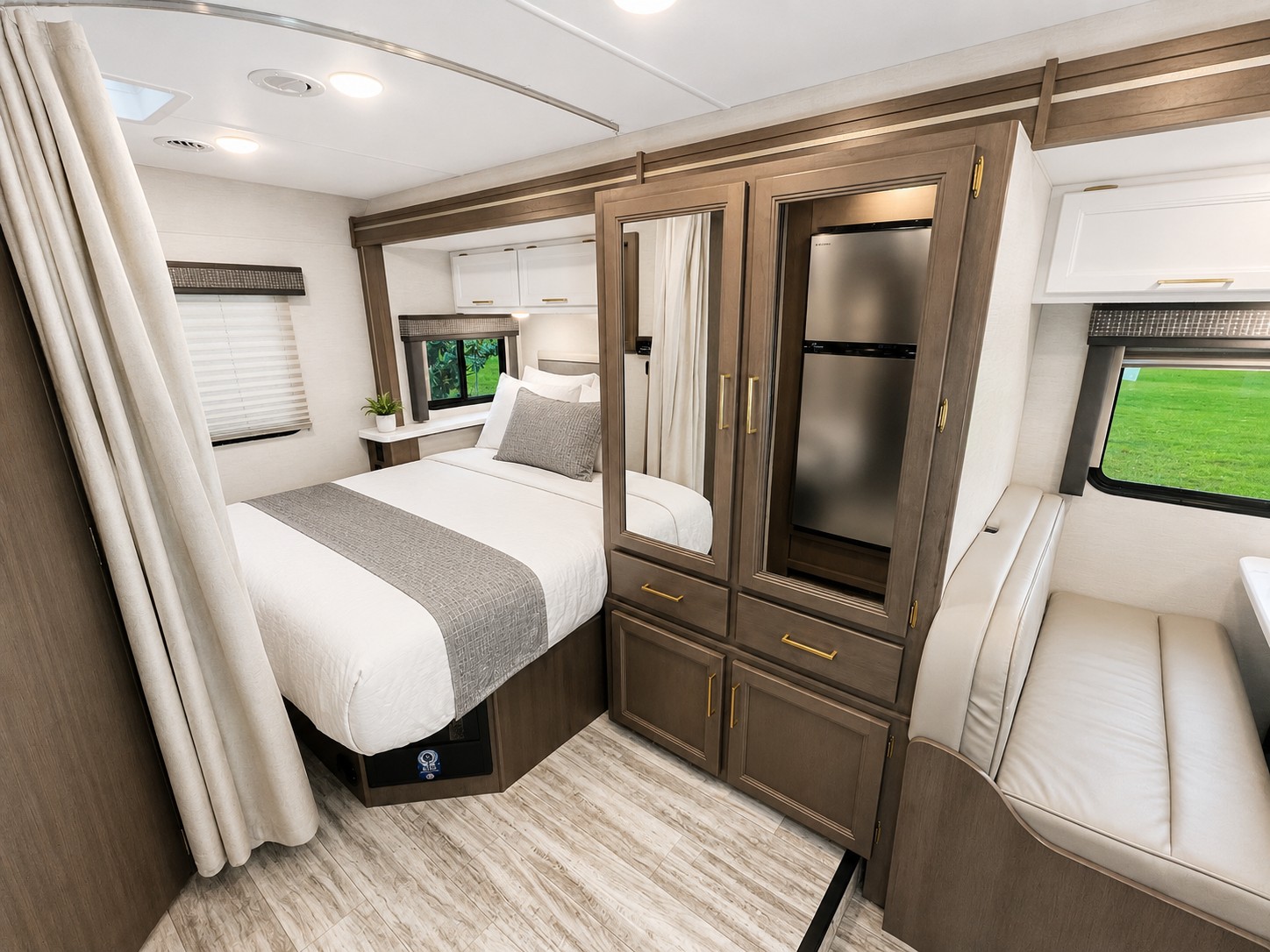 Explore this RV rental's inviting interior: a cozy bedroom with privacy curtain, adjacent dining bench, and built-in fridge.. Thor Chateau 2024