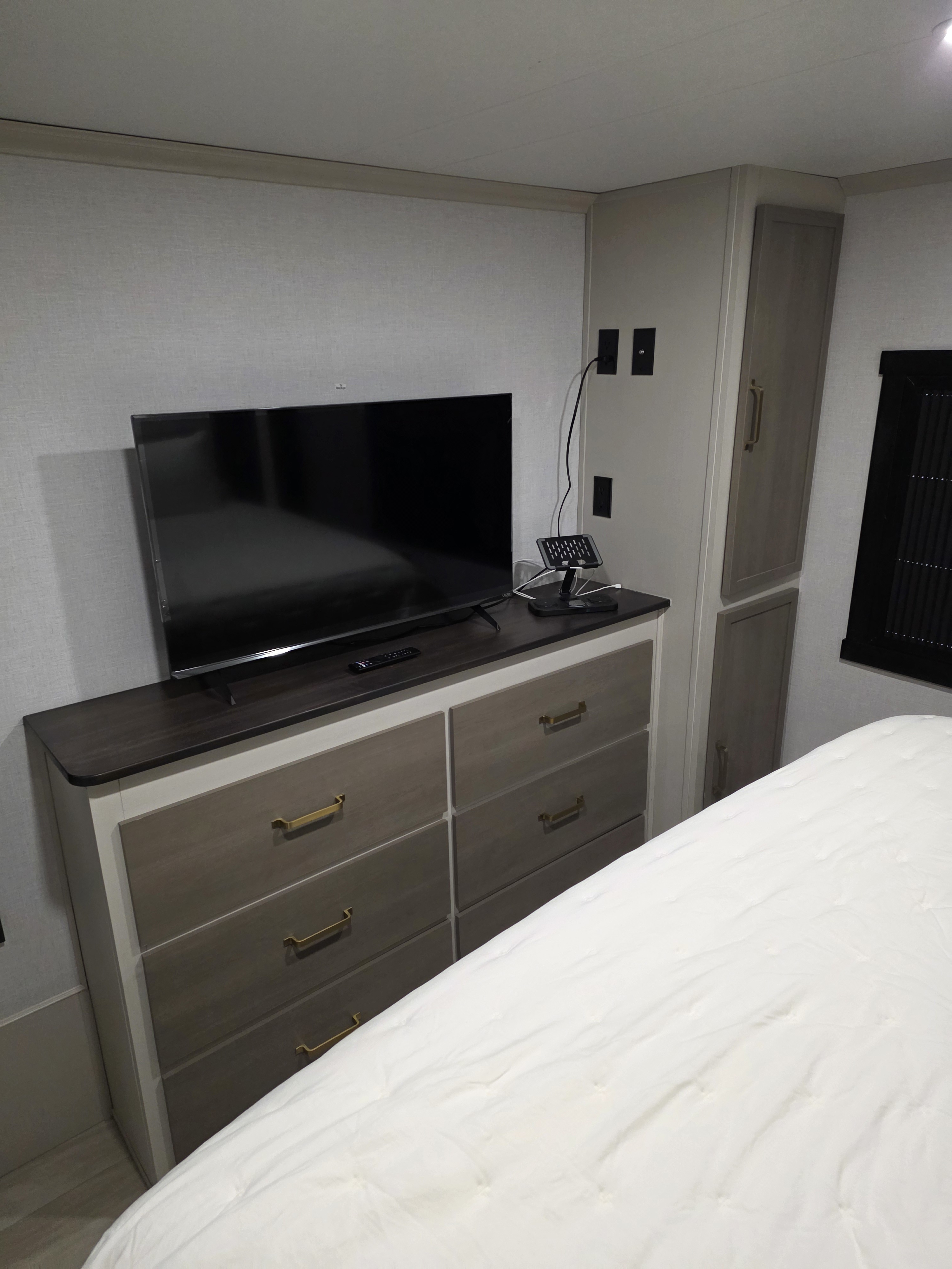 Cozy RV rental bedroom featuring a TV on a modern dresser with storage, integrated cabinets, and comfortable white bedding.. Forest River Salem Hemisphere 2025