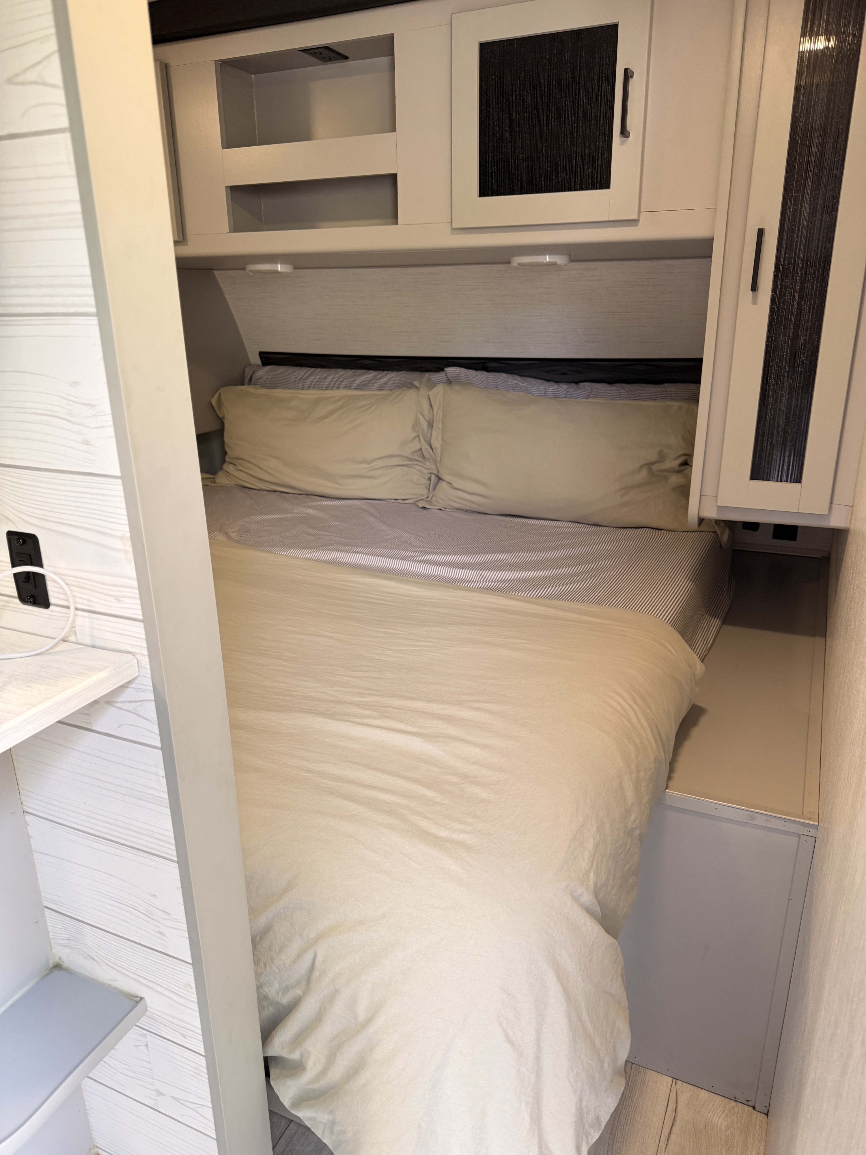 RV rental interior showing a compact, inviting bed with storage cabinets above and around it, ideal for travelers.. Heartland RVs North Trail 2022