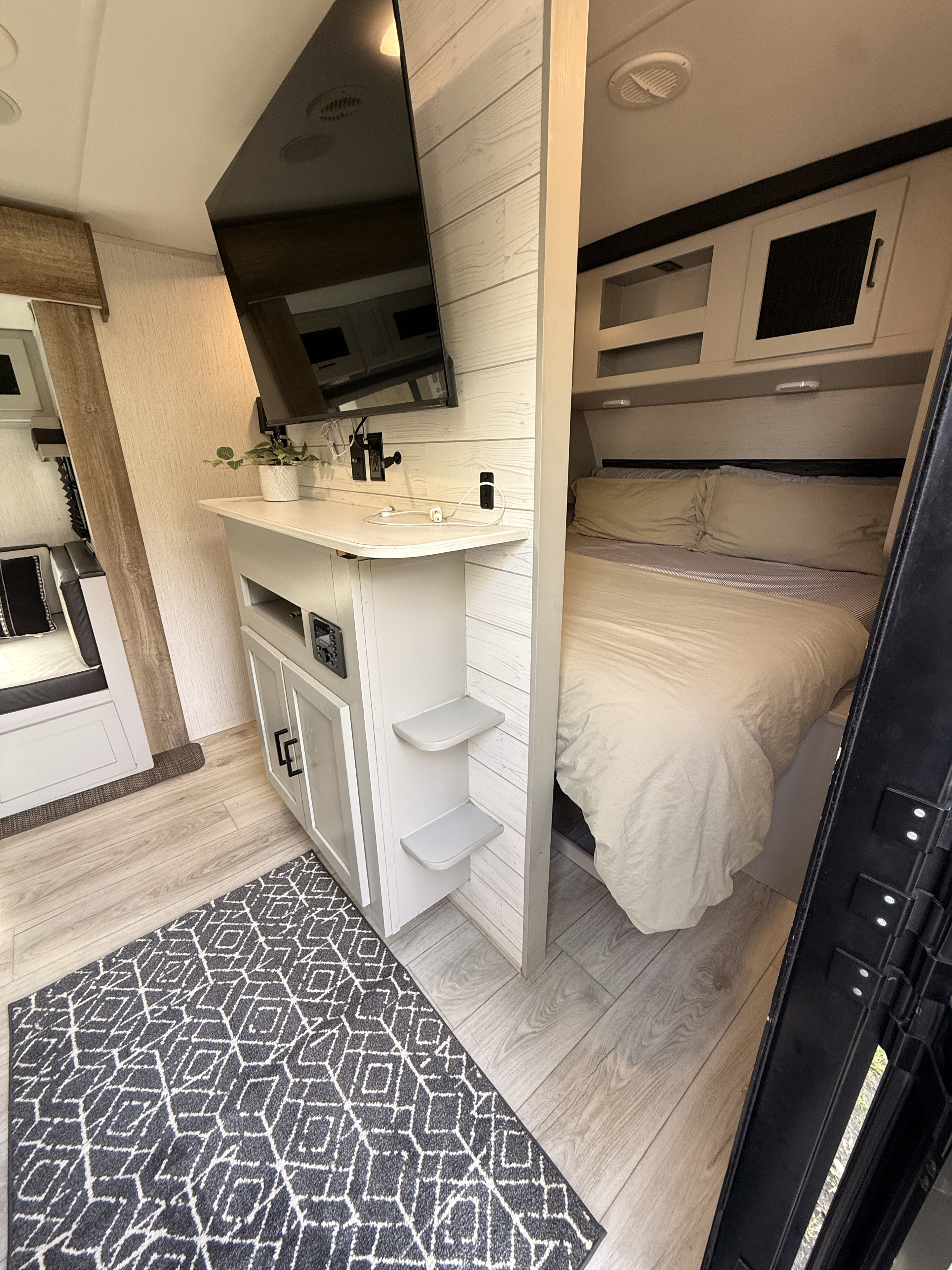 Cozy RV rental interior with a bright bedroom, wall-mounted TV, and modern wood-look floor.. Heartland RVs North Trail 2022