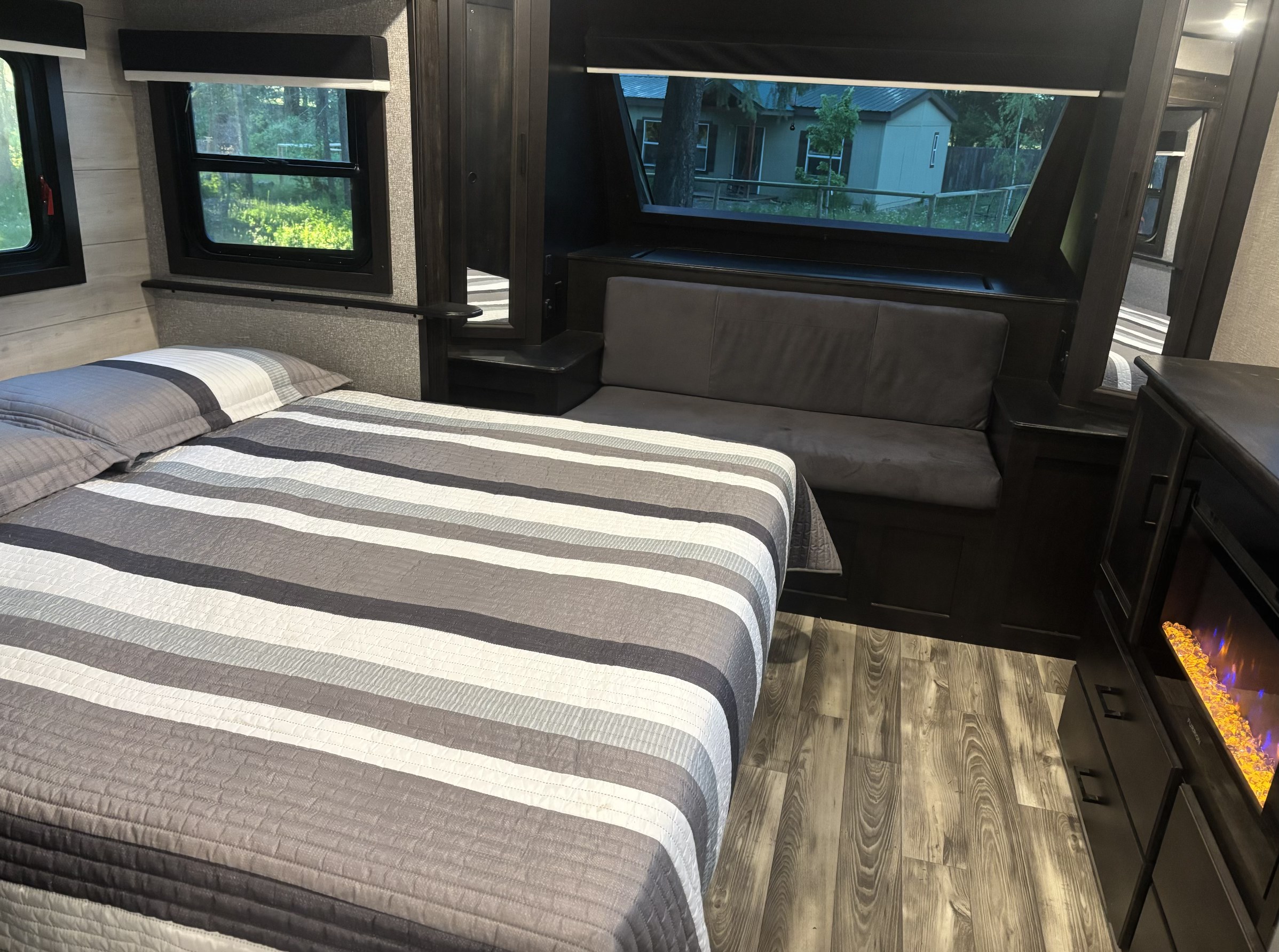 Experience comfort in this RV rental's cozy bedroom featuring striped bedding, large windows, and a warm fireplace.. Jayco Eagle HT 2023