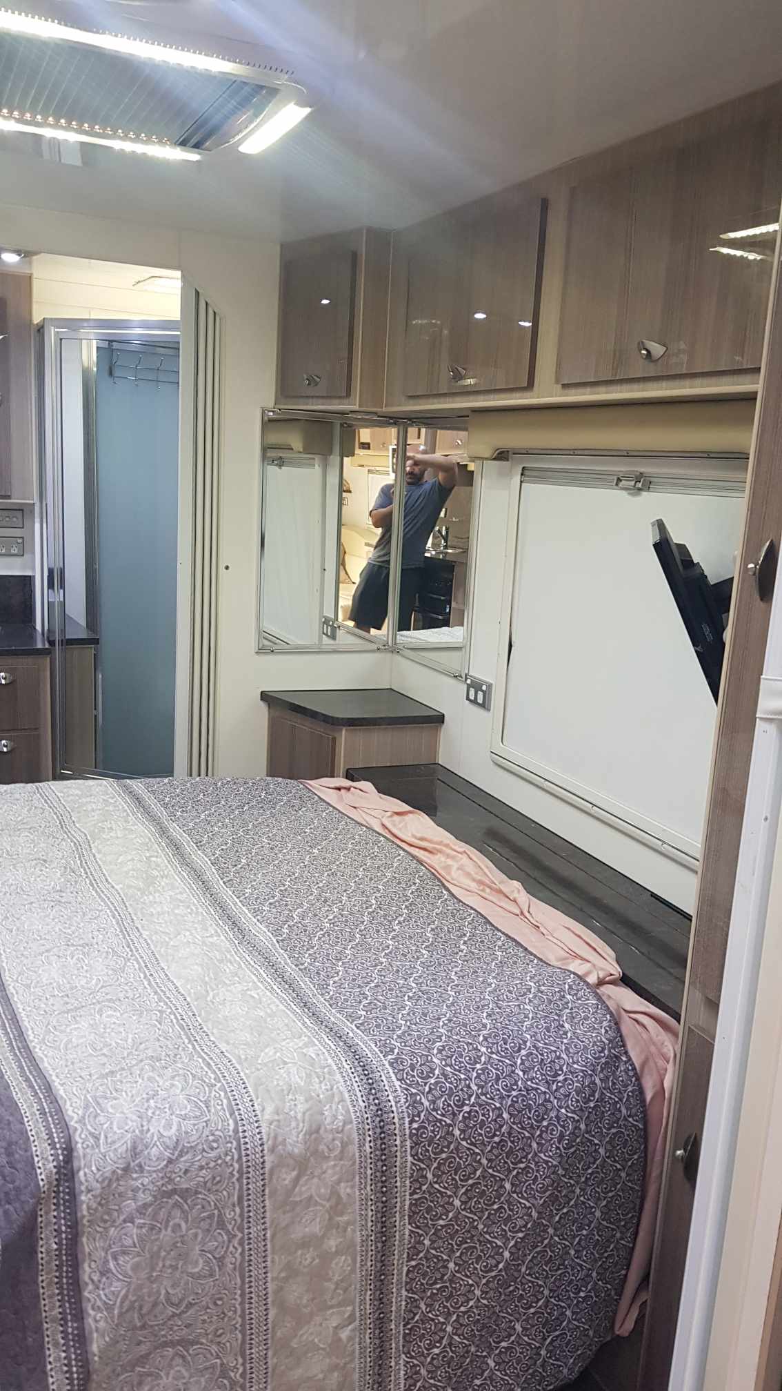 Step into this comfy RV rental bedroom featuring a patterned bed, mirrored vanity, and modern bathroom access. Your adventure starts here!. Sonic Sonic Trailer 2016