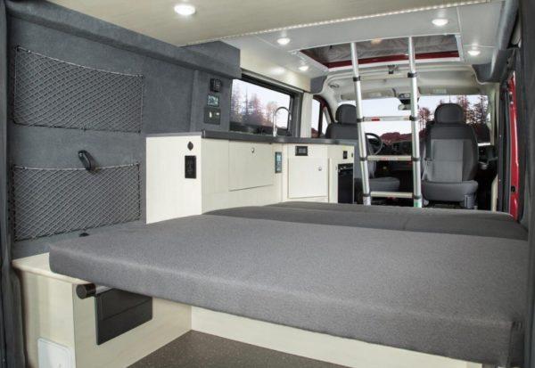 Modern rv rental interior showing a comfortable bed, galley kitchen, front cabin, and overhead ladder for adventure.. Pleasure-Way Pleasure-Way Class B 2022