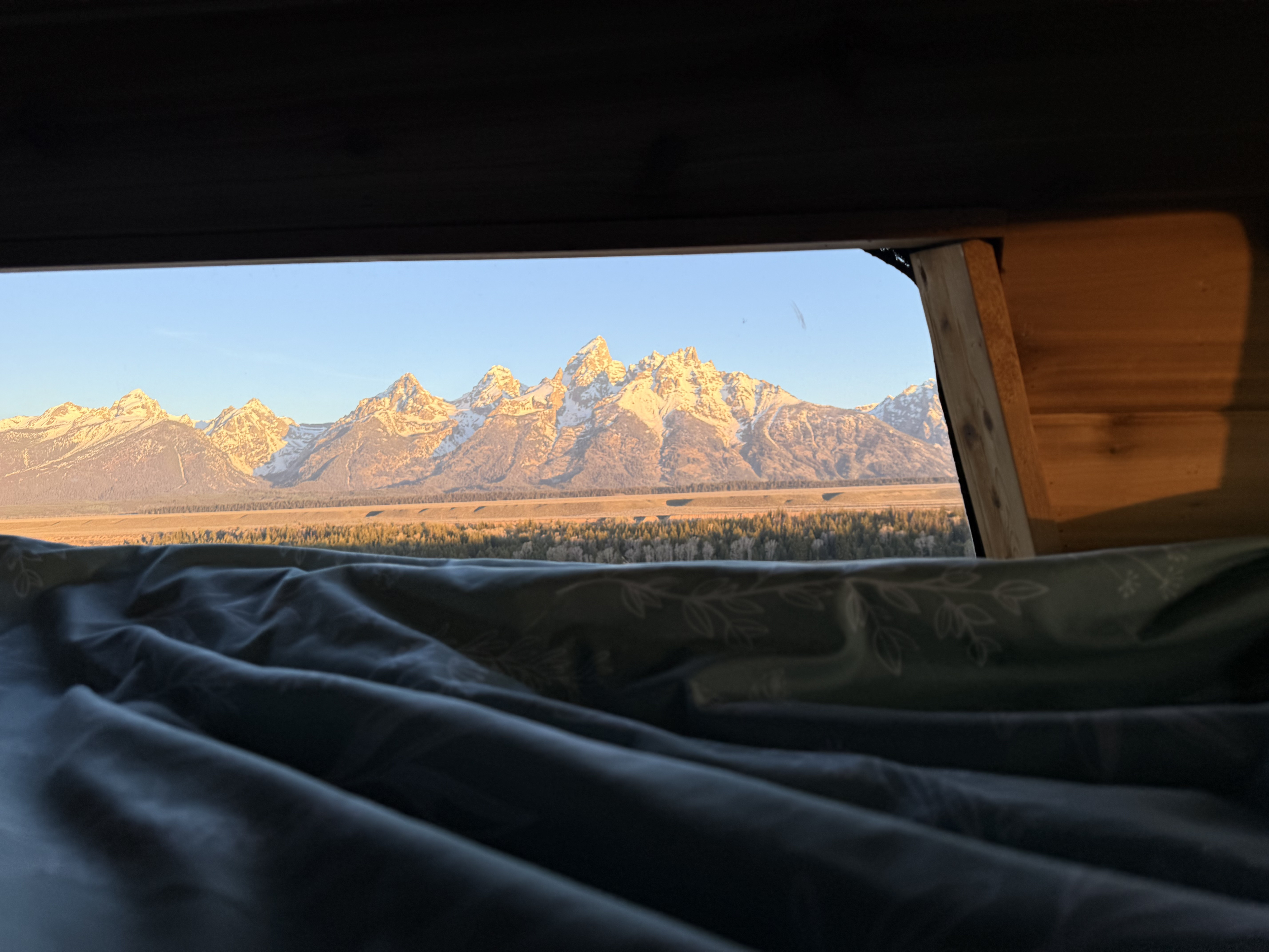 Stunning Grand Teton mountains at sunrise from an RV rental bed. Perfect nature view for your next adventure.. Ford Econolline 250s 2001