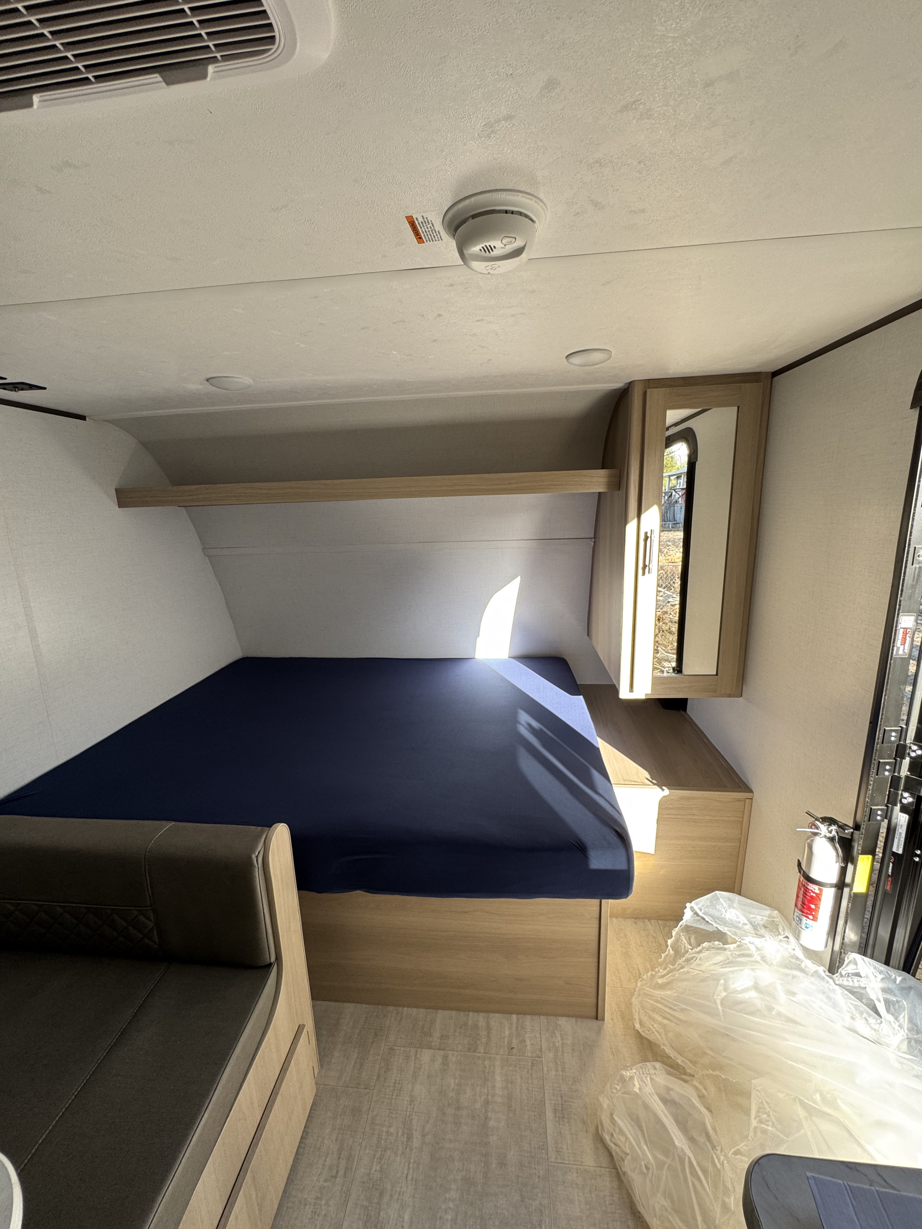 Inside an RV rental: a compact bedroom with a blue bed, dinette, and mirrored cabinet, ready for adventure.. Kodiak 178BHS 2026