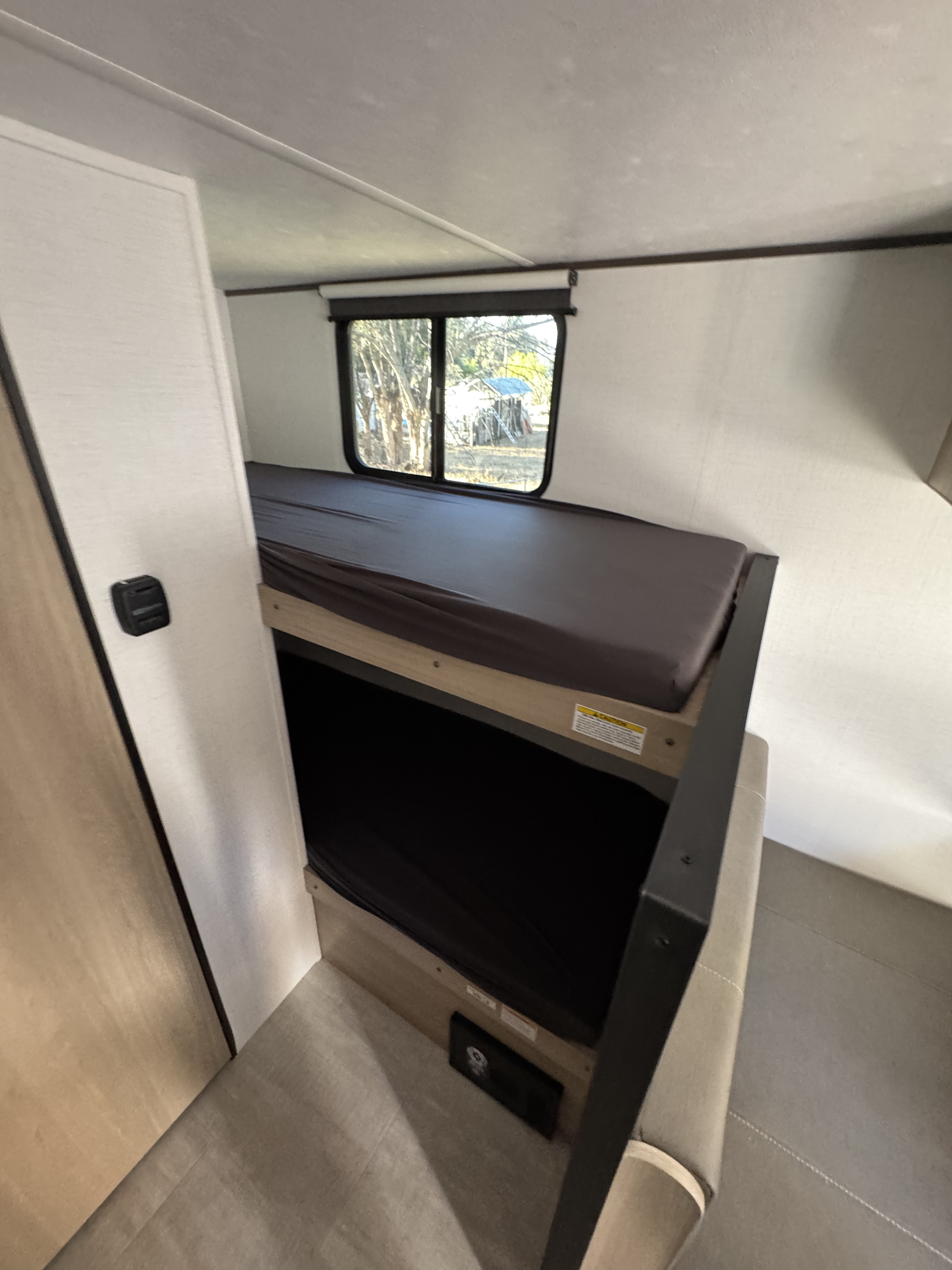 View of an RV rental's interior, featuring bunk beds, a window with an outdoor view, and a built-in seating section.. Kodiak 178BHS 2026