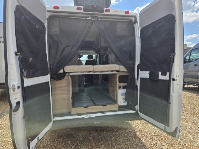 Rear view of an RV rental with back doors open, revealing the interior bed, storage, and a protective mesh screen.. Winnebago Solis 2023