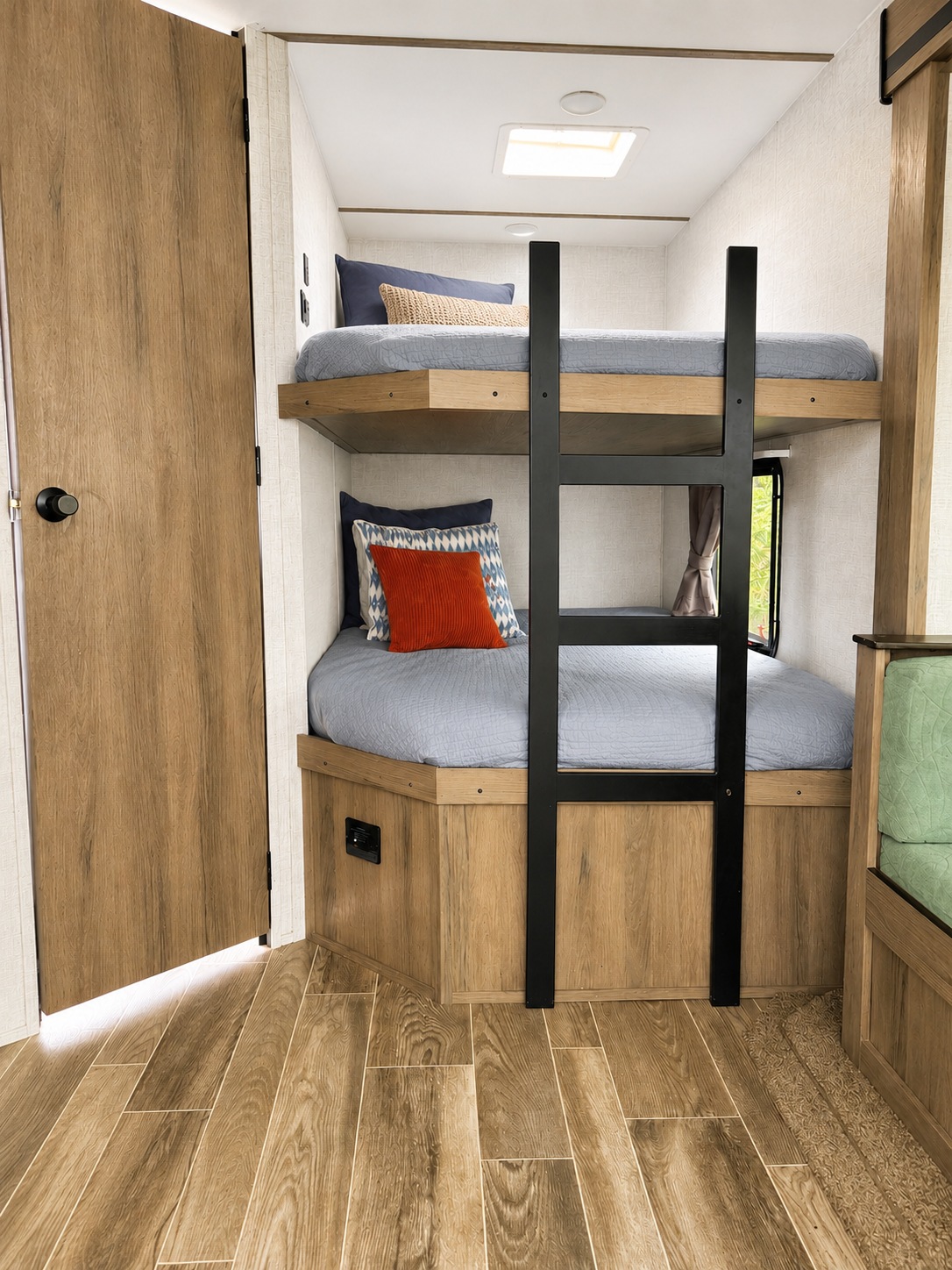 This rv rental shows a compact sleeping area with two bunk beds, light wood finishes, and blue bedding; a ladder provides access to the top bunk.. Gulf Stream Enlighten 2021