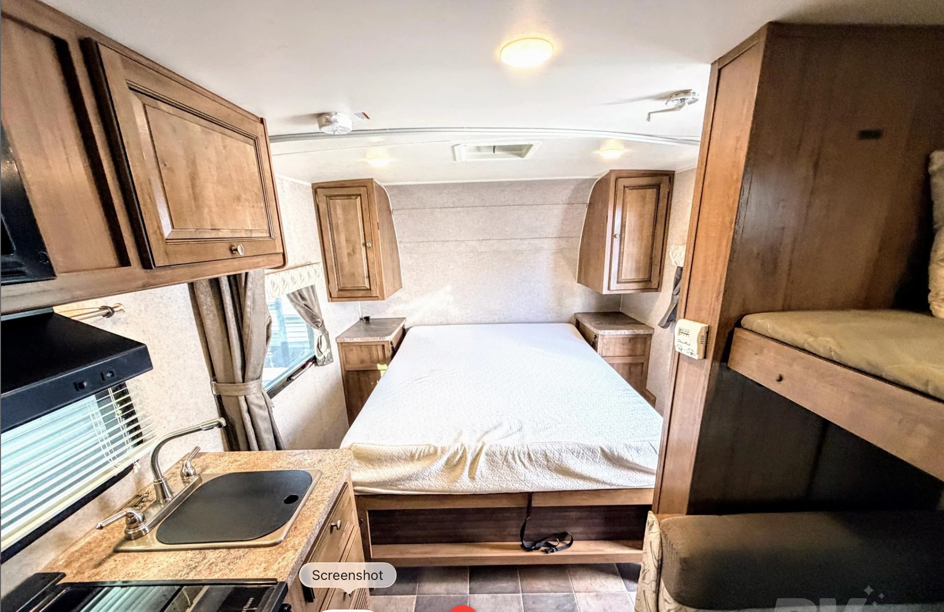 This RV rental interior features a cozy bedroom with overhead storage, a functional kitchen counter with a sink, and bunk beds.. Forest River Flagstaff Micro Lite XLT 2017