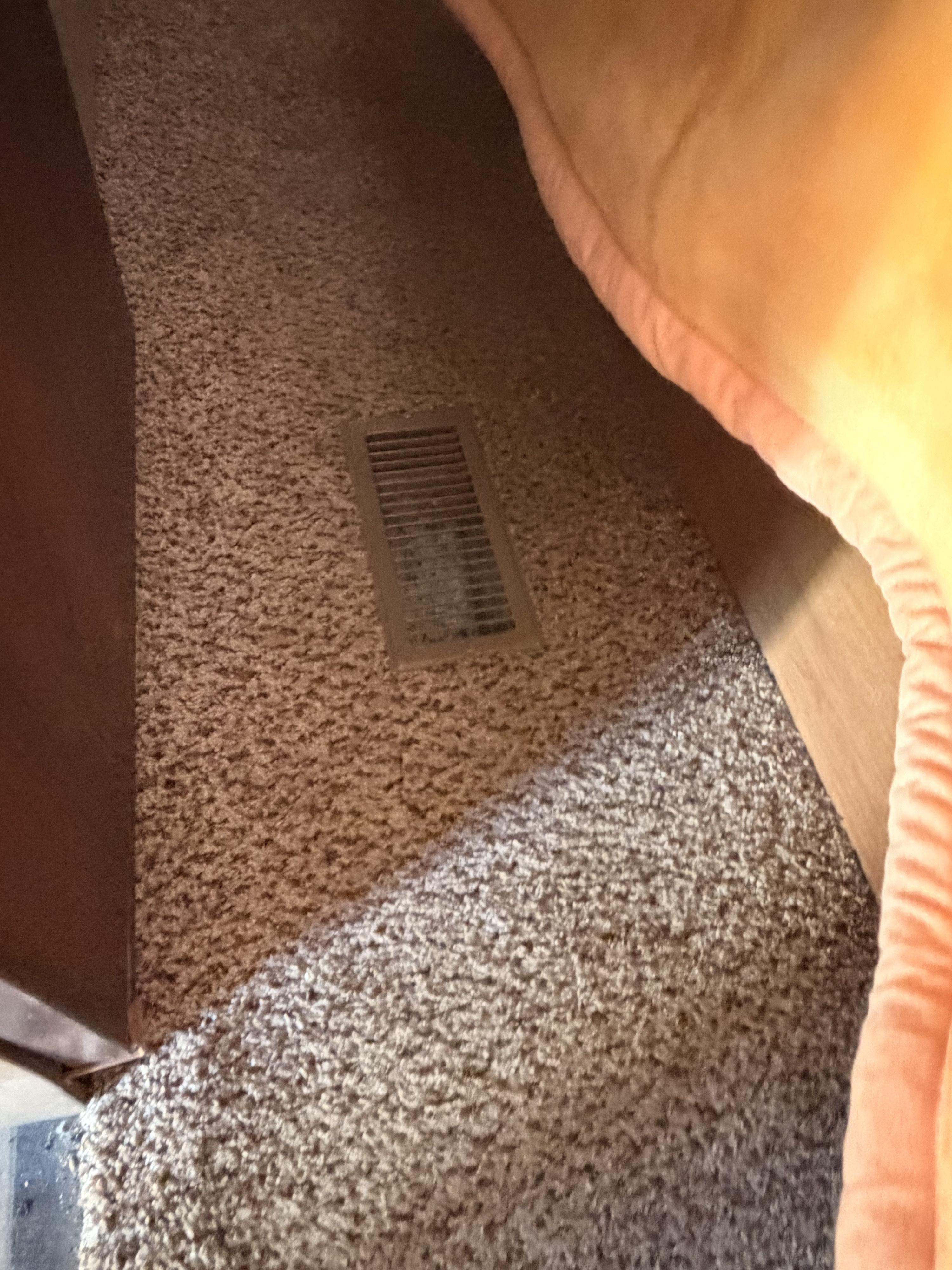 Inside an RV rental: a floor vent on speckled carpet, next to a cozy, orange-trimmed cushion.. Keystone RV Outback 2011