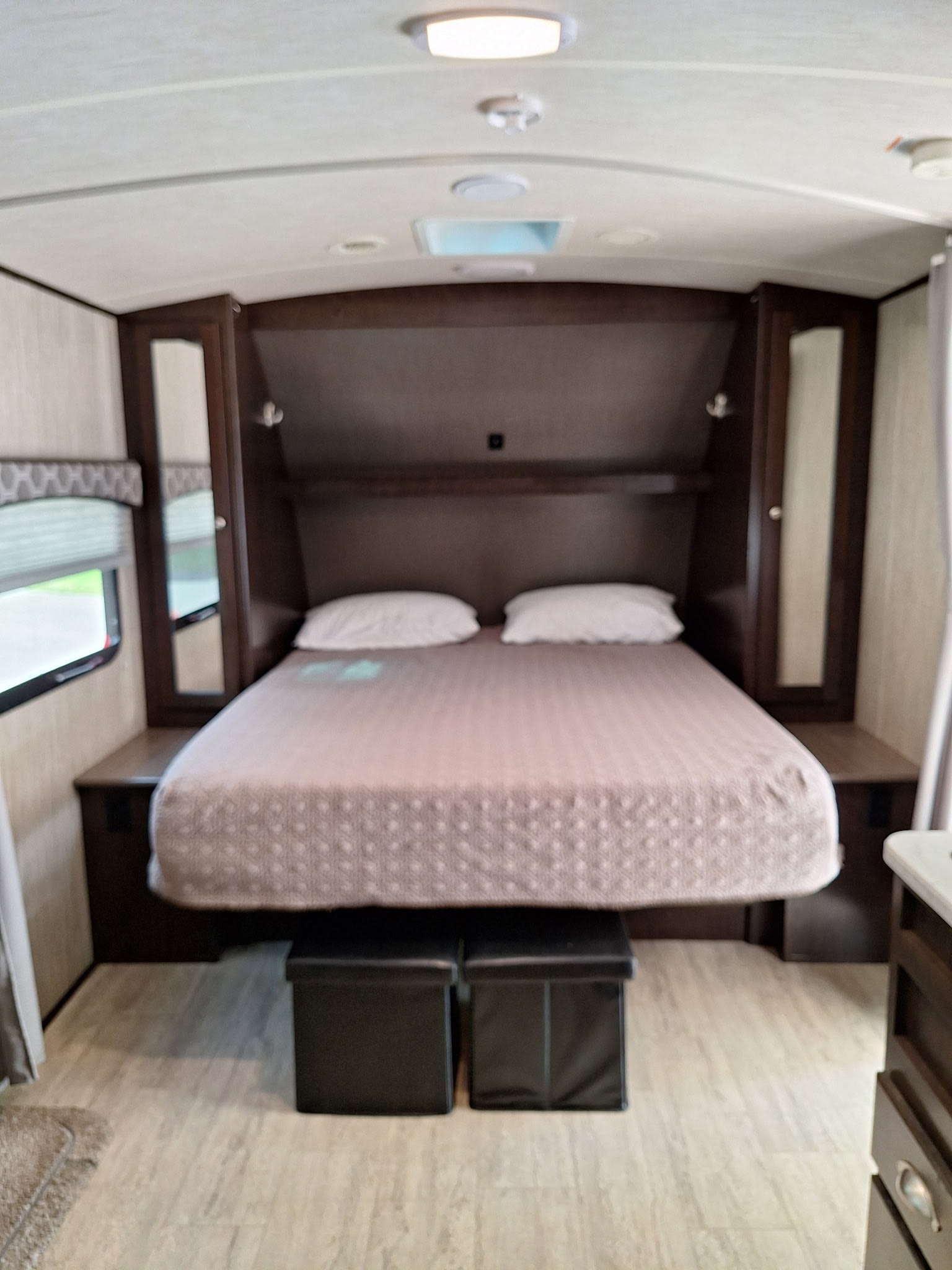 Cozy RV rental bedroom with a queen bed, two storage ottomans, and built-in cabinets. Perfect for your next adventure.. Cruiser RV Shadow Cruiser 2018