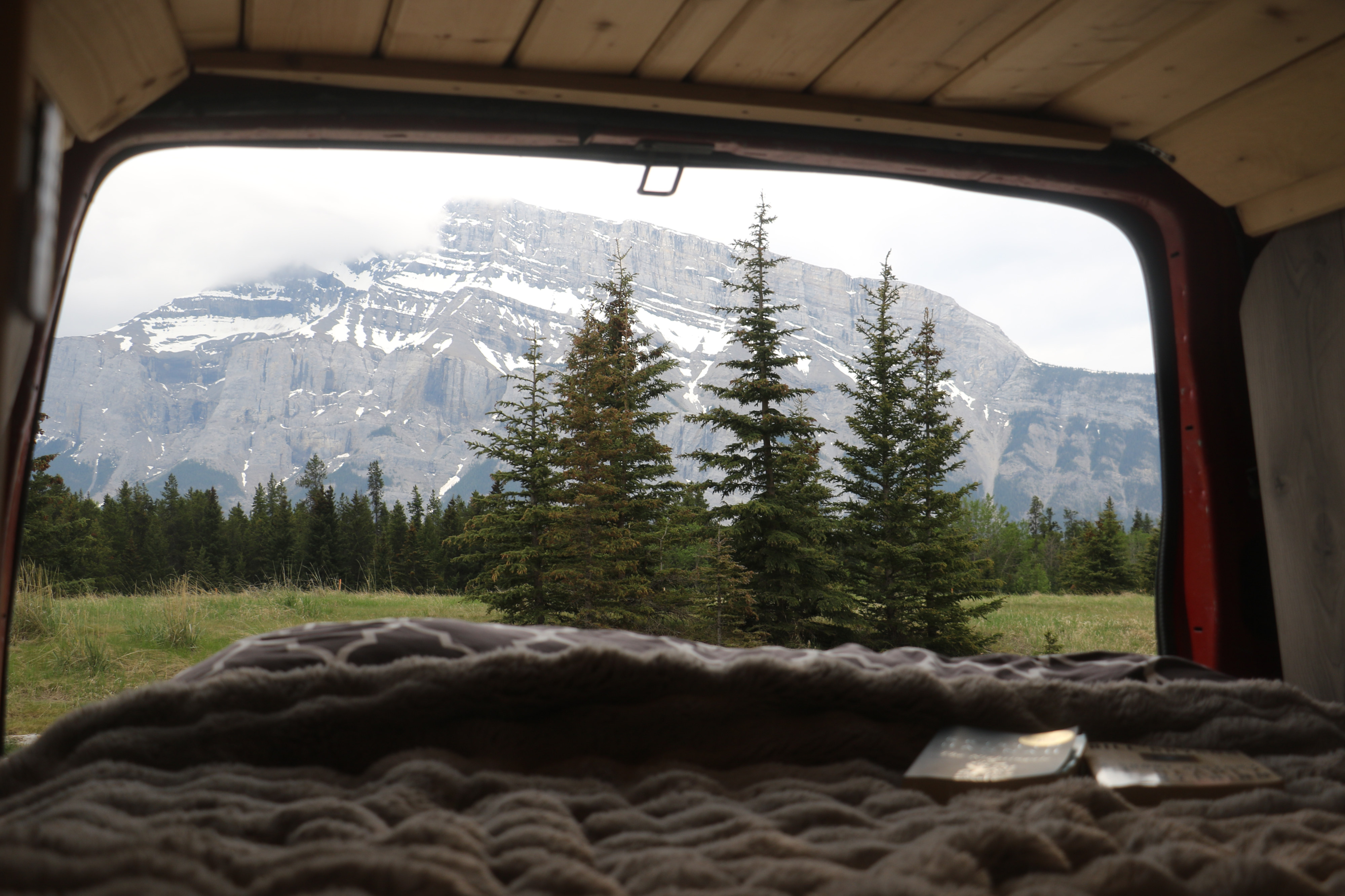 Relax in your RV rental with a breathtaking mountain and forest view from the cozy bed. Ideal for serene nature getaways.. Glacier Campers Vanlife Explorer 2013