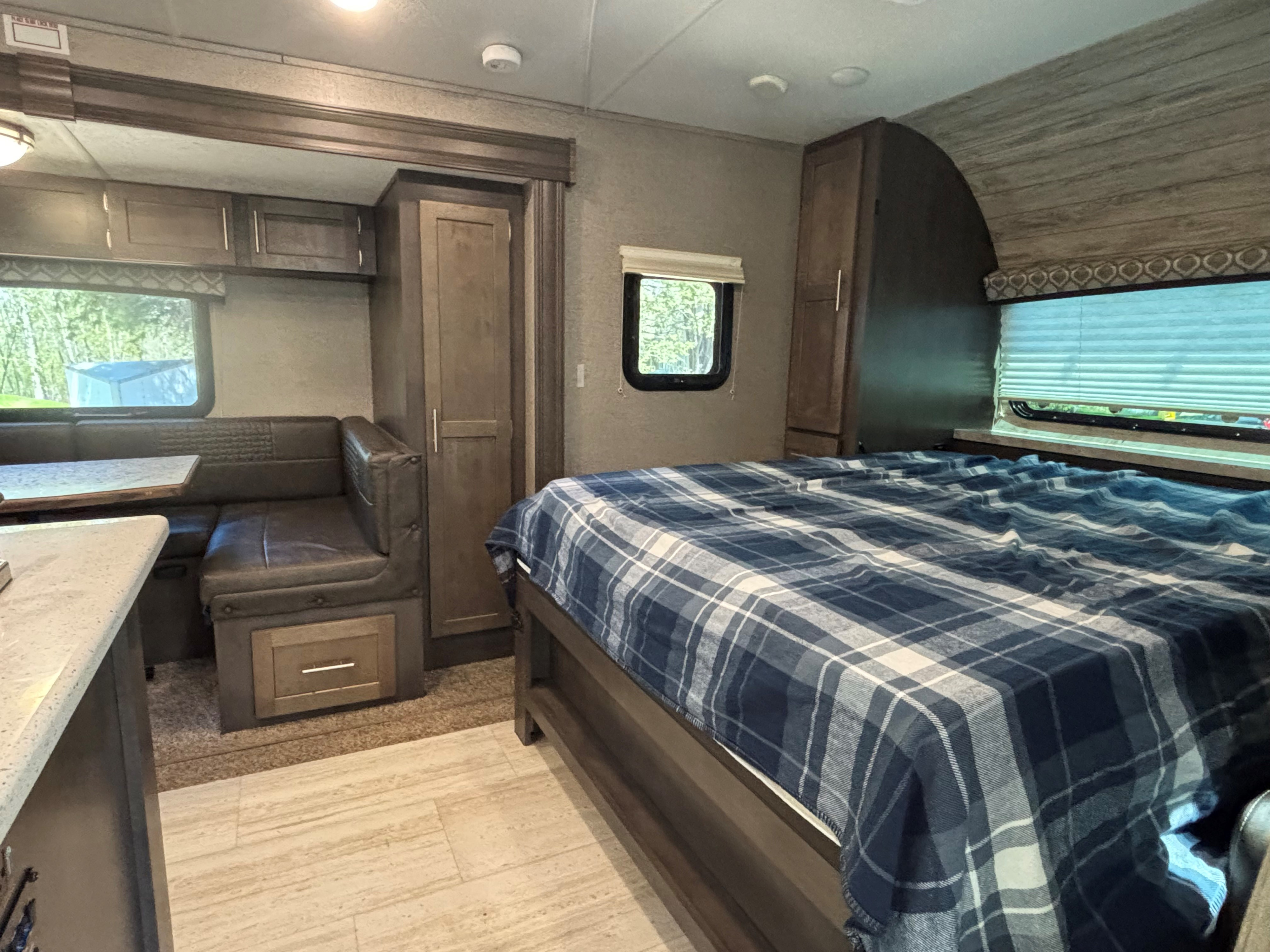 An RV rental interior showing a cozy bed with blue plaid and a dinette area for comfortable travels.. Forest River Flagstaff Micro Lite 2019