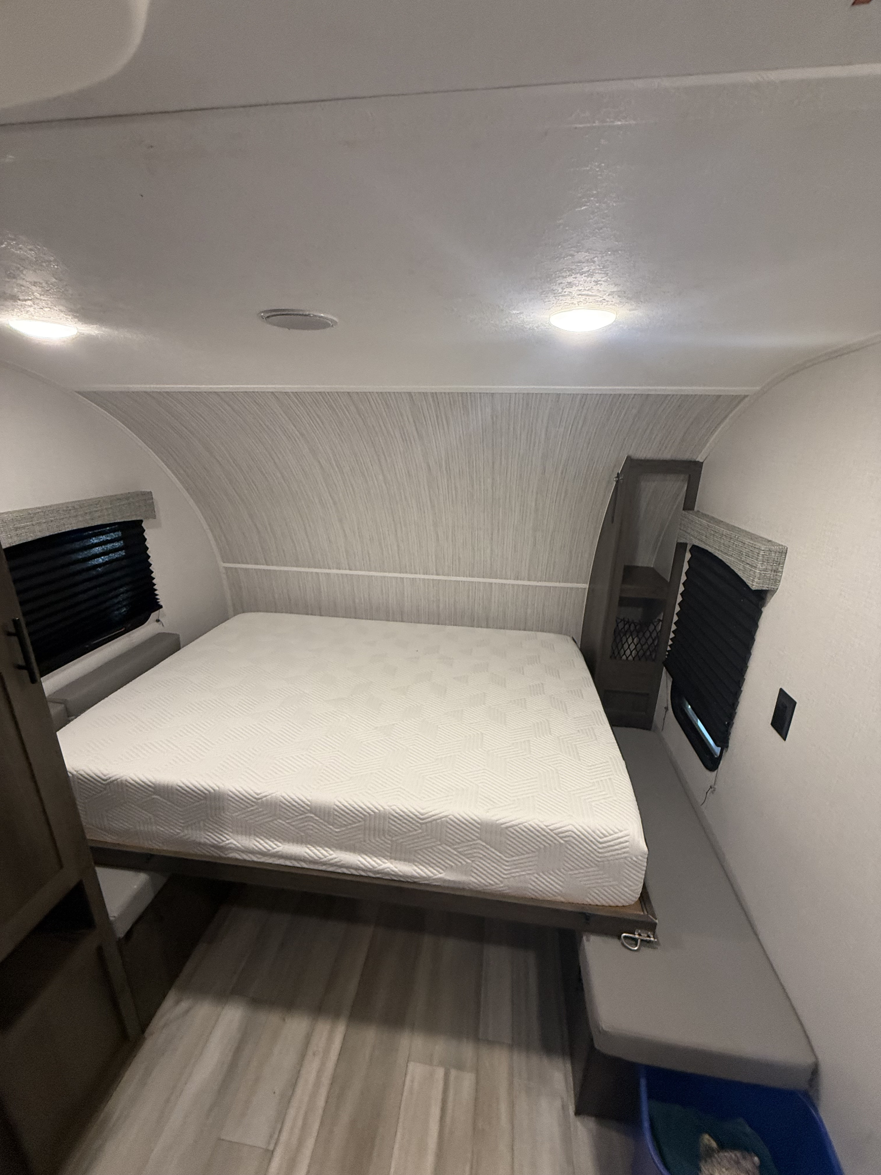 Compact RV rental bedroom interior, featuring a white bed, windows with blinds, overhead lighting, and storage.. Clipper Ultra Lite 2022