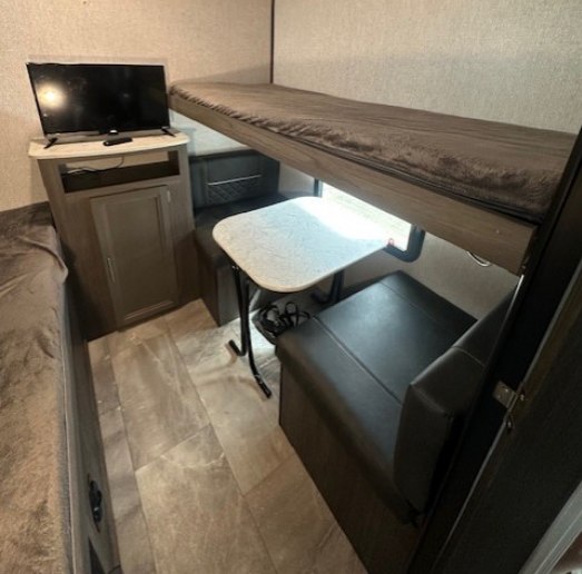 RV rental interior features bunk beds, a dinette, and TV setup, perfect for family travel trailer adventures.. Dutchmen Kodiak SE 2021