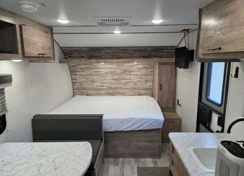 This modern RV rental interior features a cozy bed, dinette, and kitchenette. Wood-look accents and ample storage visible.. Gulf Stream 177bh 2026