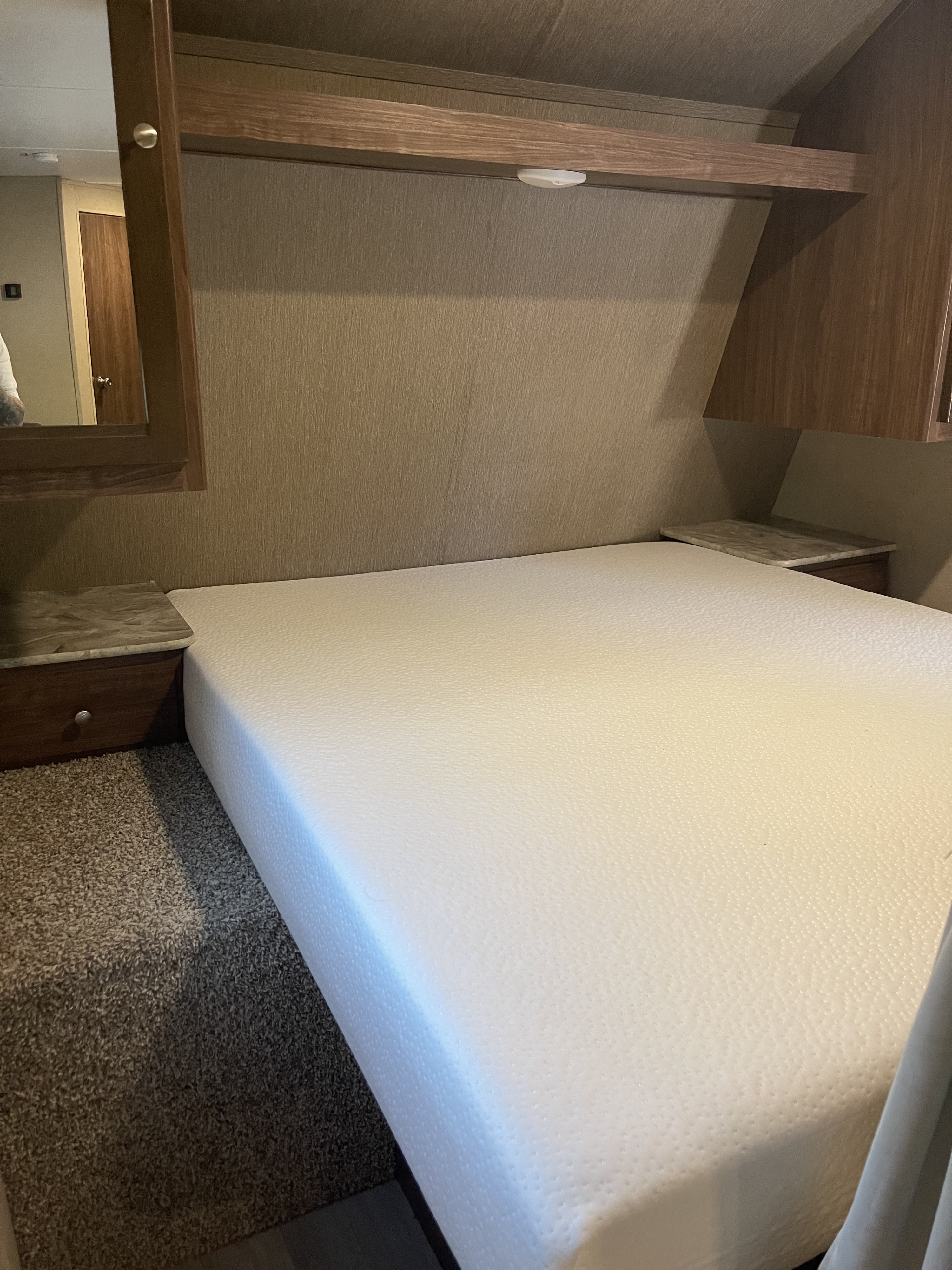 Cozy RV rental bedroom featuring a queen memory foam mattress, overhead storage, and built-in nightstands.. Dutchmen Coleman Lantern 2018