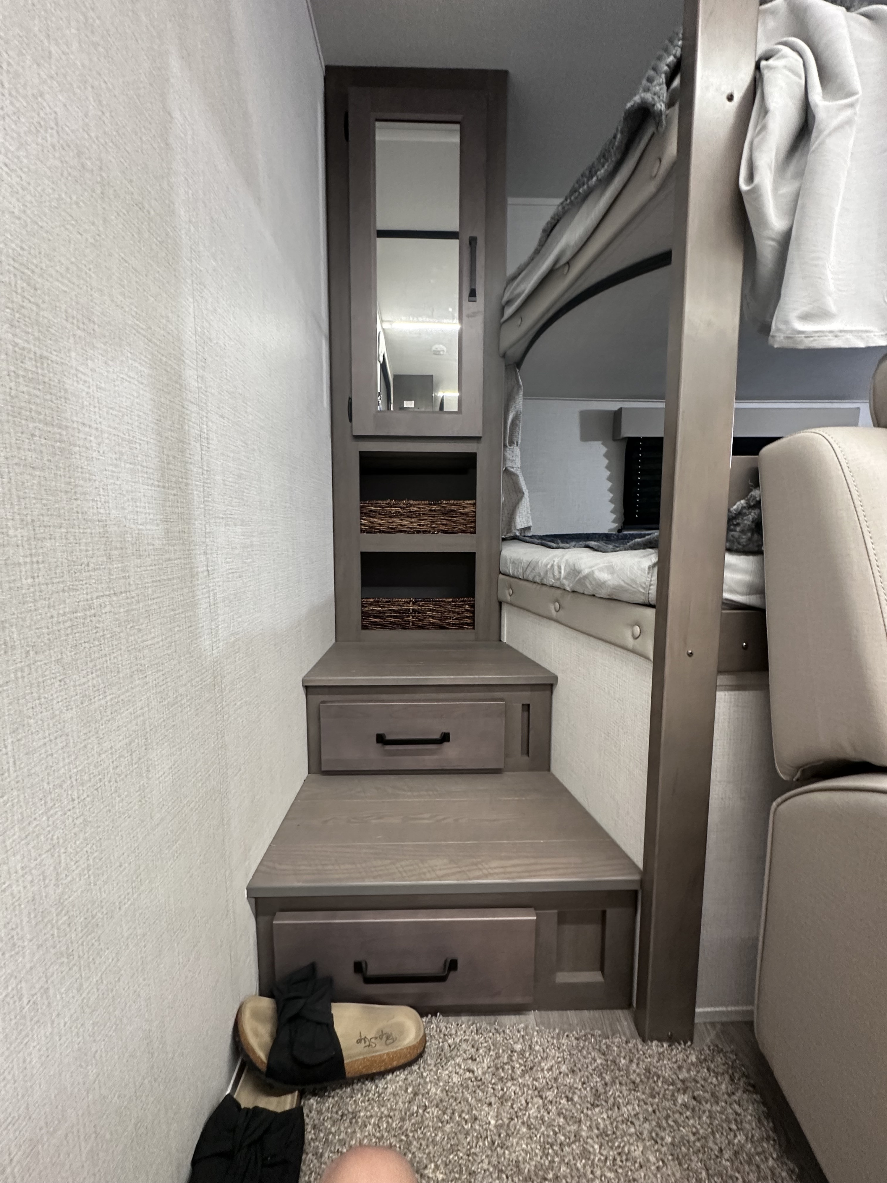 Inside this rv rental, find bunk beds, convenient storage steps with a mirrored cabinet, shelves, and drawers, optimizing space.. Grand Design Transcend Xplor 2024