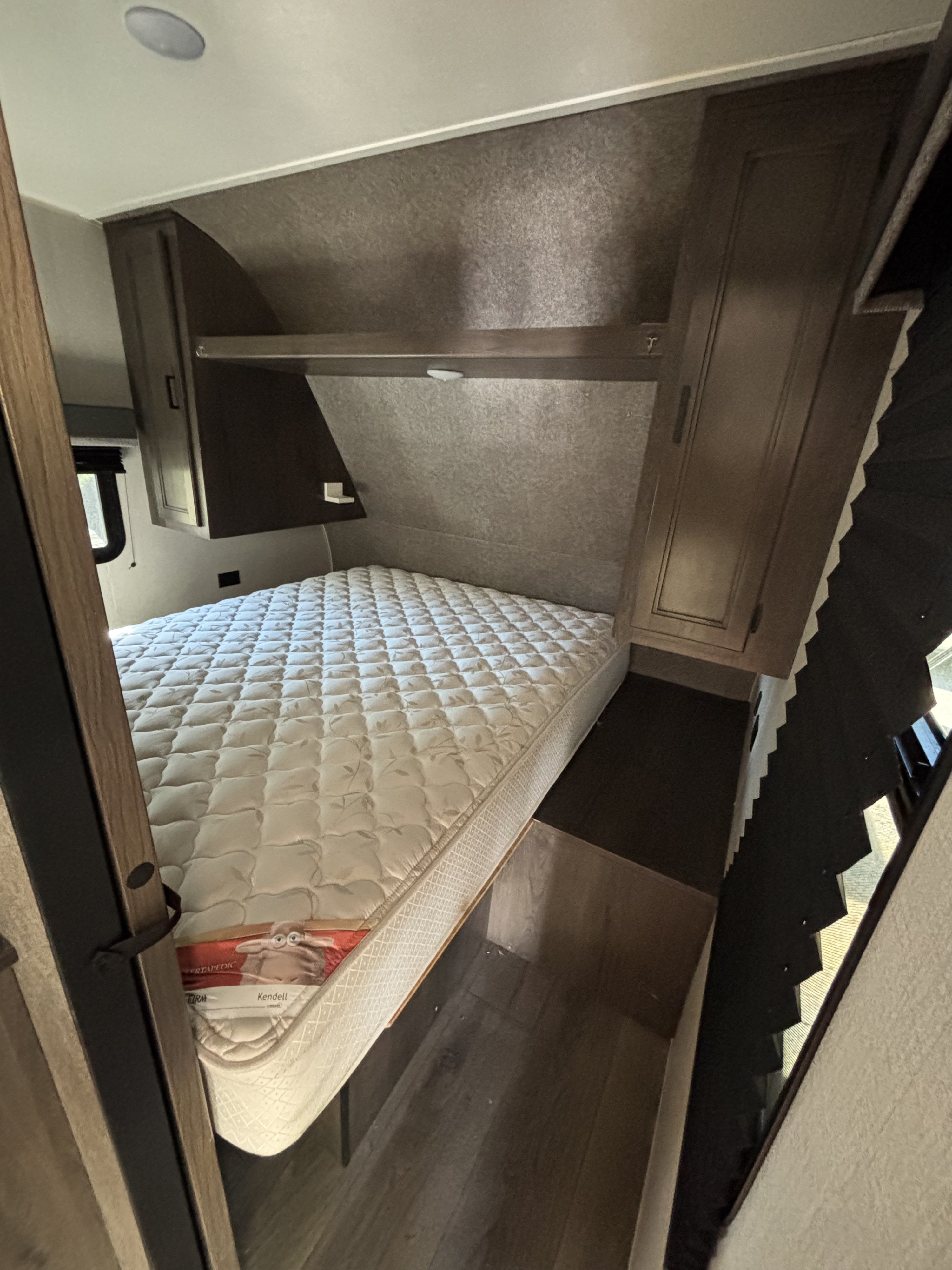 Cozy RV rental bedroom featuring a comfortable bed, overhead storage, and window blinds, designed for compact living.. Highland Ridge RV Open Range 2021