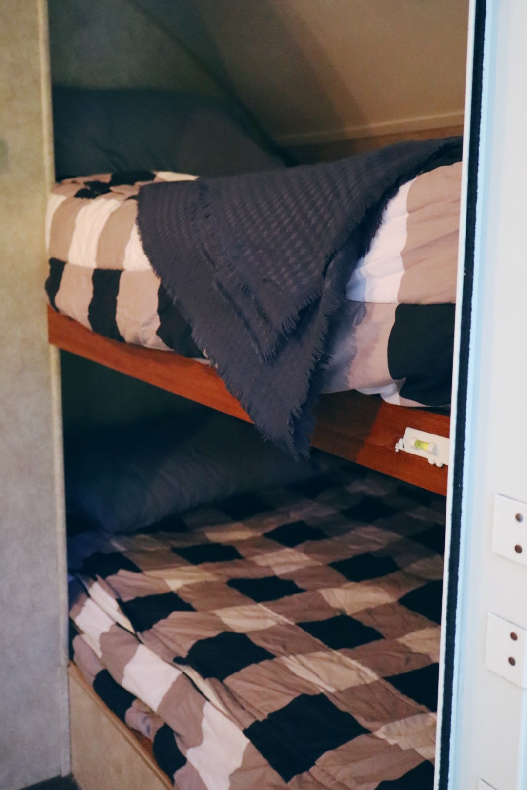 Cozy bunk beds in an RV rental interior, featuring checkered bedding and a practical spirit level on the upper bunk frame.. Forest River R-Pod RP-172 2010